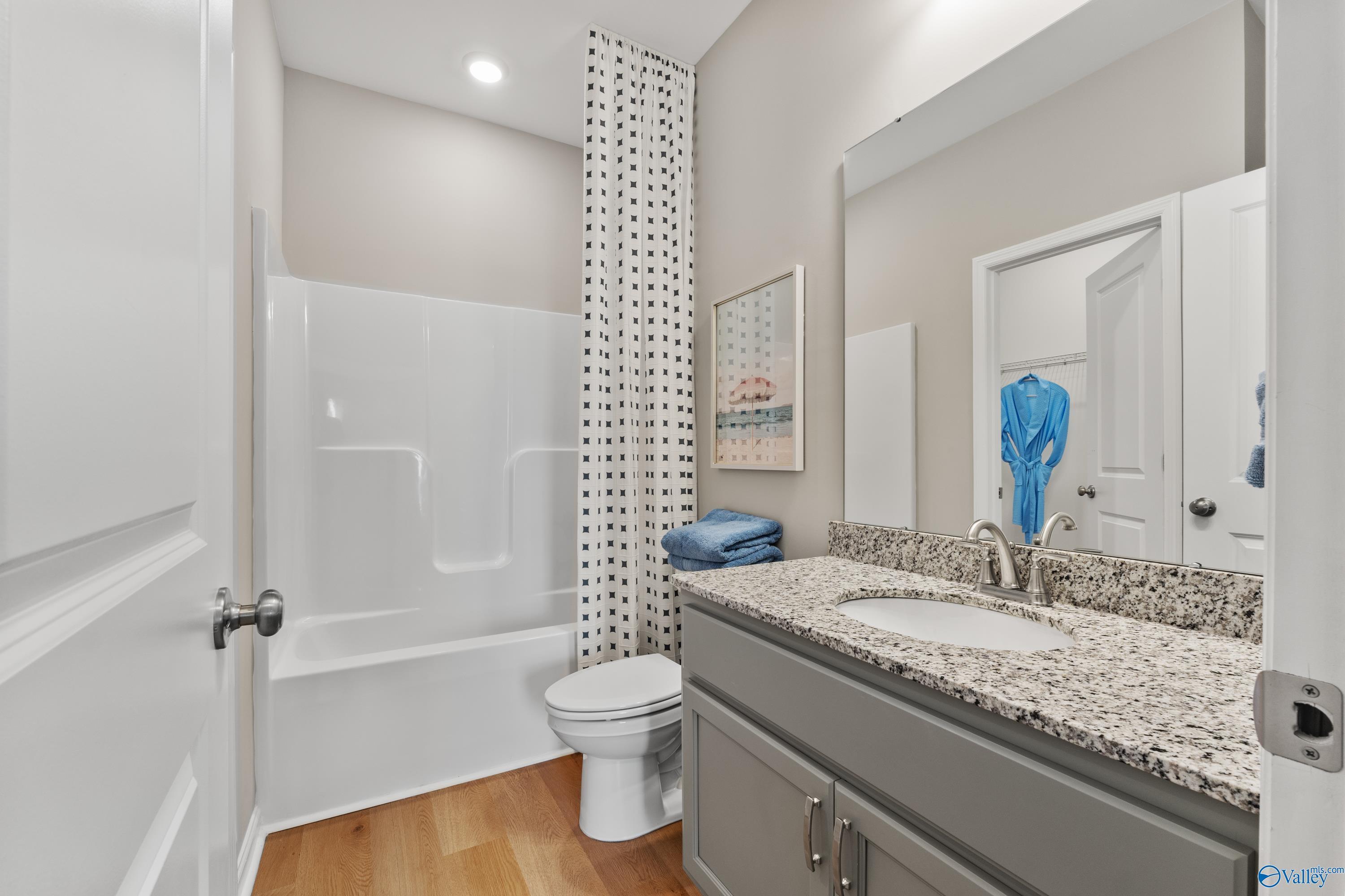 Modern bathroom with granite vanity, white tub-shower combo, and blue accents in 4-bedroom Davidson Homes The Sanctuary, Athens, Alabama