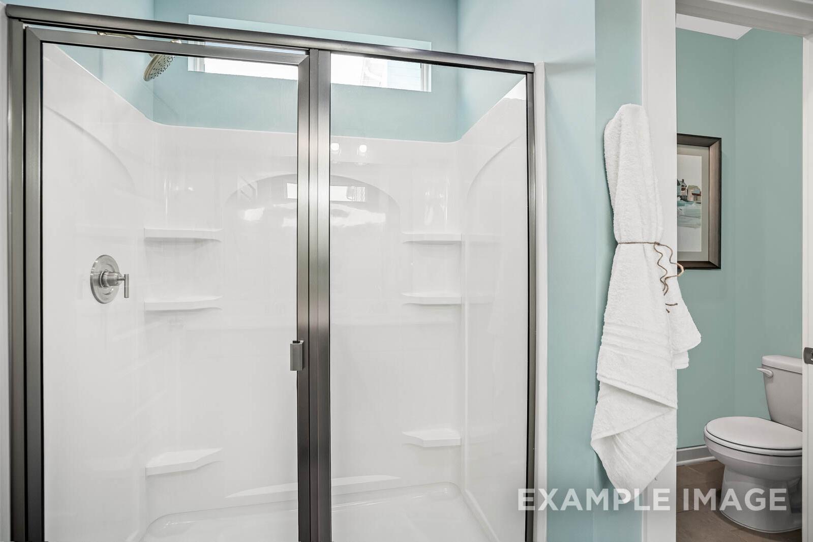 Spacious master bath in The Franklin B featuring frameless glass shower, white tiles, built-in shelves, and towel rack