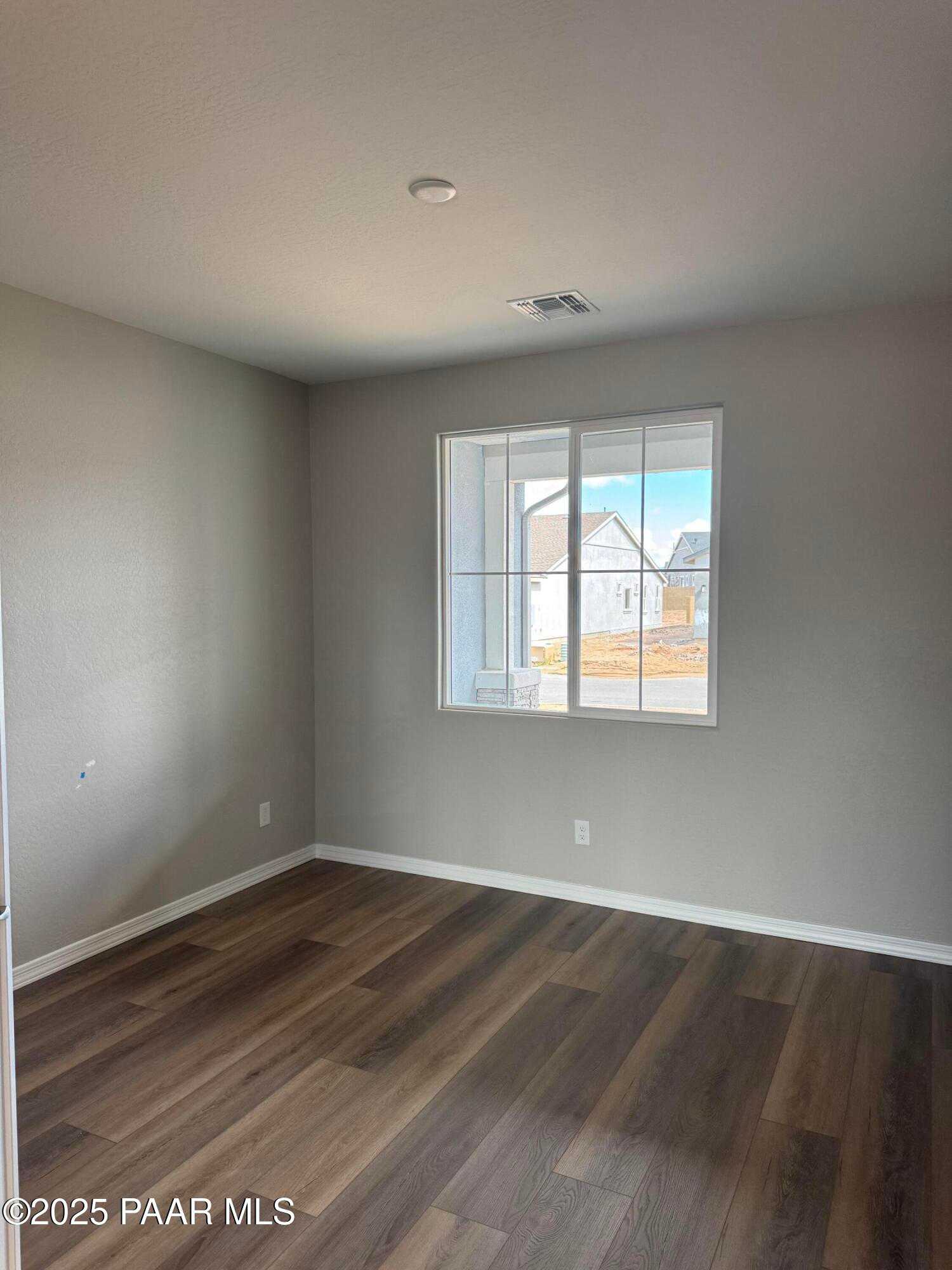 Bright secondary bedroom with large window, beige walls, and laminate wood flooring in Davidson Homes The Monarch A, Prescott, AZ