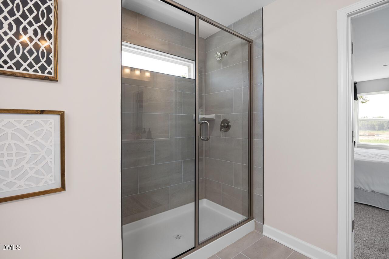 Modern frameless glass shower with gray subway tile and window in master bathroom, The Hickory II C by Davidson Homes, Zebulon NC