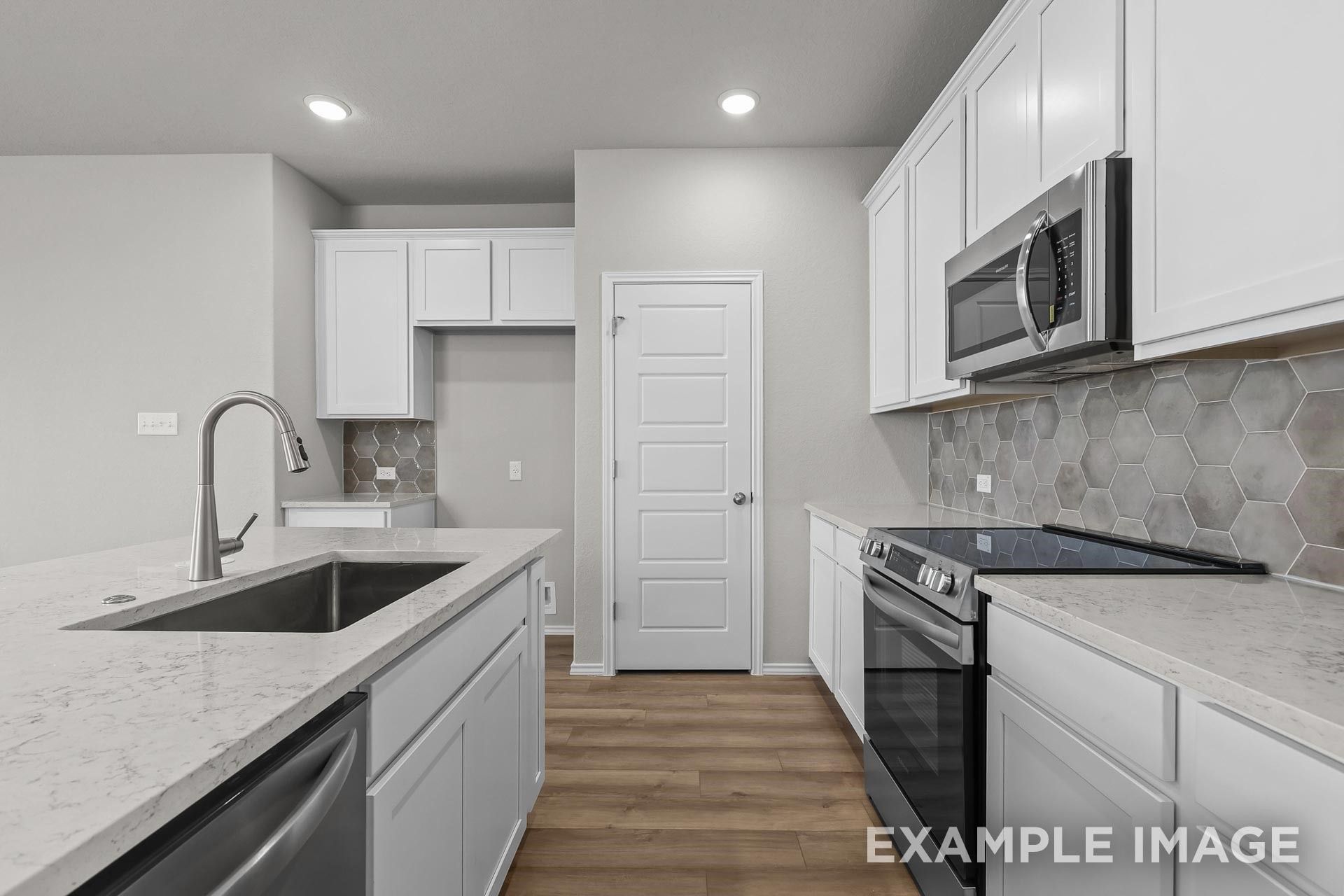 Modern kitchen with white cabinets, quartz countertops, and hexagon backsplash in The Colorado G home in Heartland, Texas.