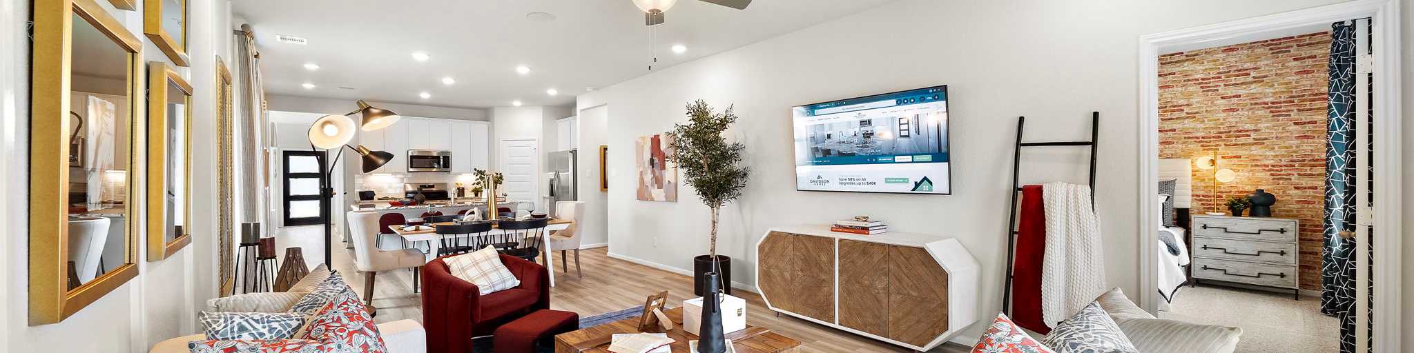 Modern open-concept living room in new Lavon home with beige sofas, wooden coffee table, large TV, plants, and recessed lighting