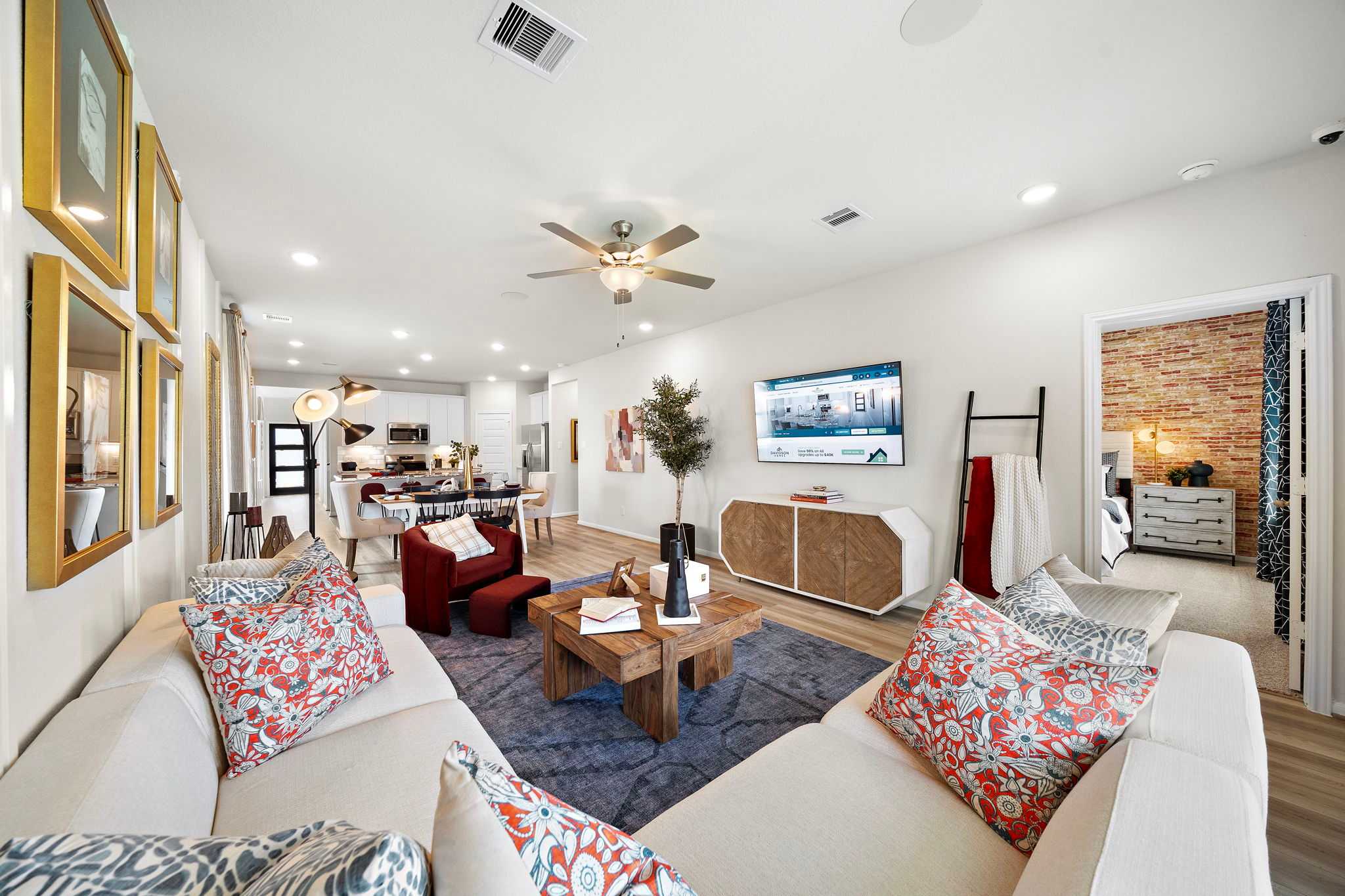 Spacious open-concept living room in Liberty Estates Cleveland TX home by Davidson Homes with modern sofa, TV wall, and brick accent