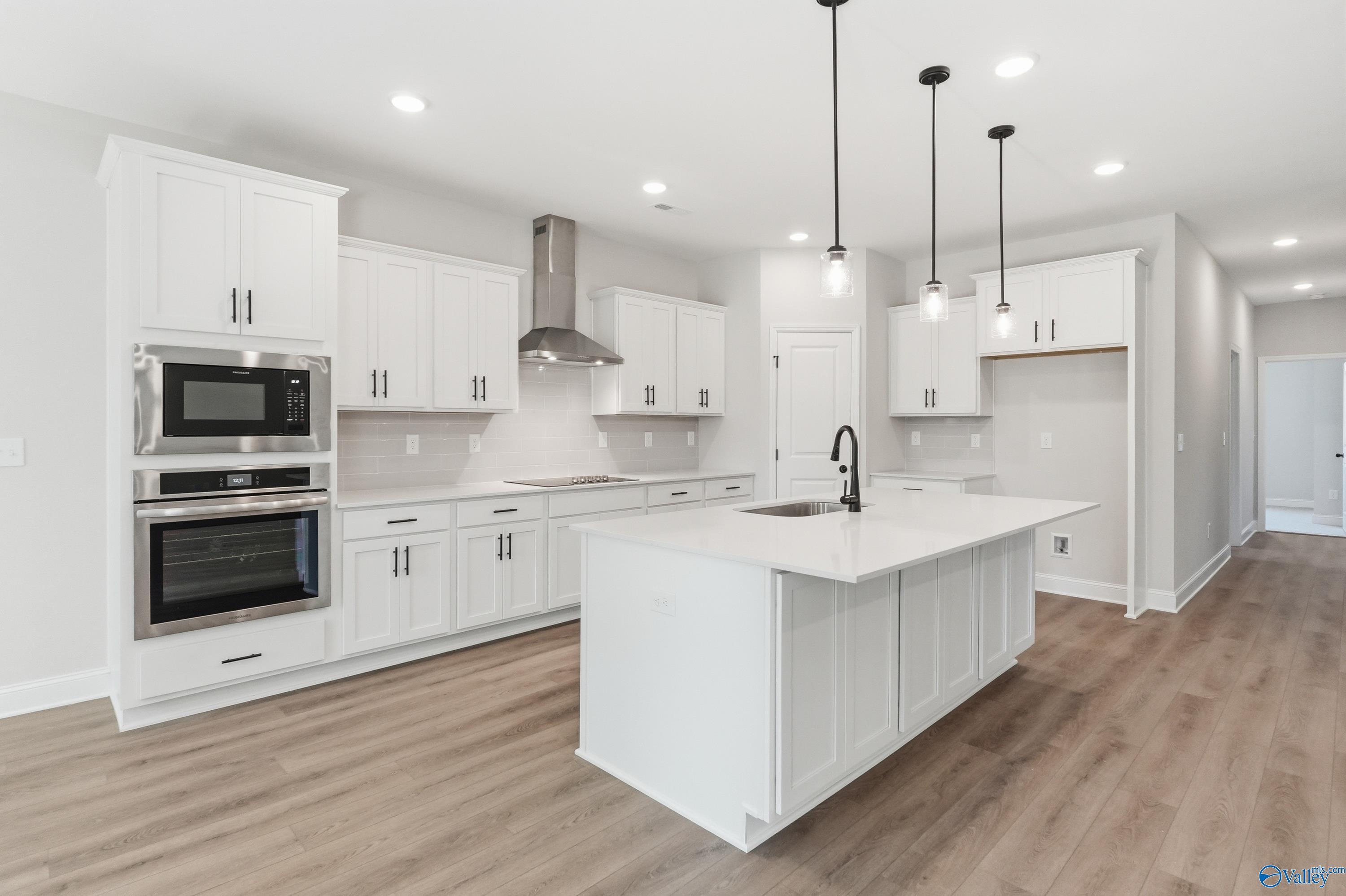 Modern white shaker kitchen with quartz island, double oven, stainless appliances in Davidson Homes The Rockford B, Athens AL