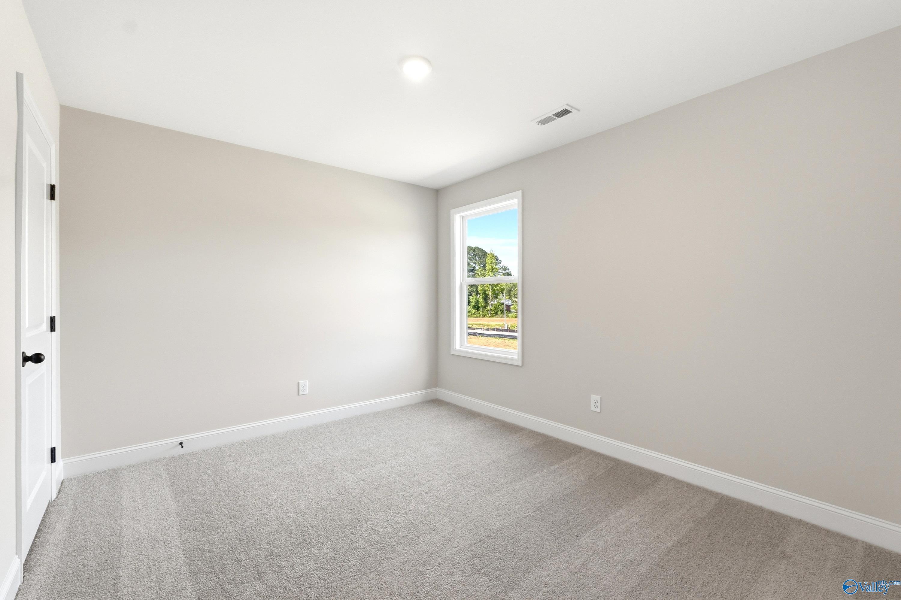 Bright bedroom with neutral walls and plush carpet in The Russell A floor plan at Spragins Cove, Huntsville, Alabama.