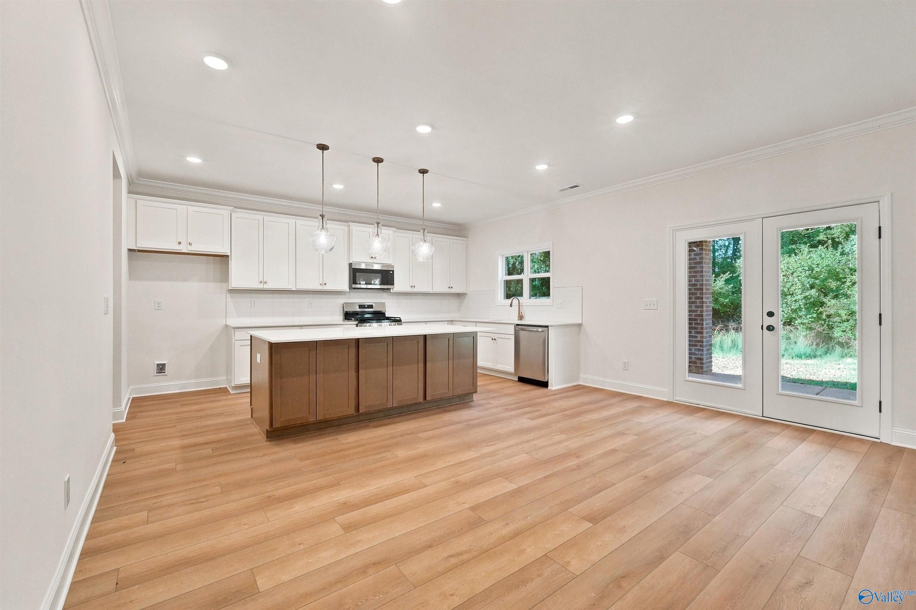 Modern kitchen with white cabinets, wood island, and pendant lighting in The Chelsea C floor plan, Creek Grove, Alabama.