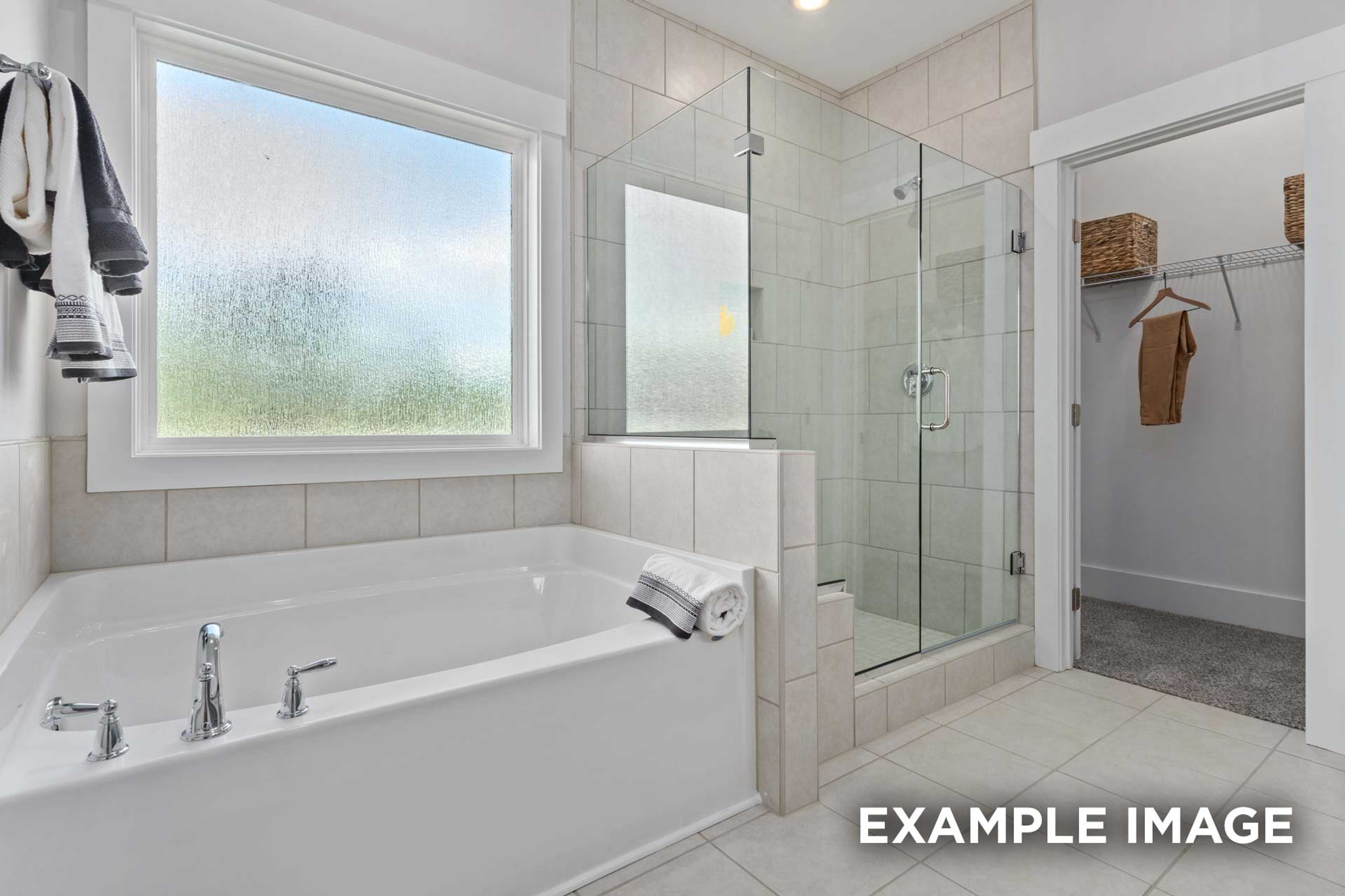 Spacious master bathroom in The Franklin C with soaking tub, frameless glass shower, and adjacent walk-in closet