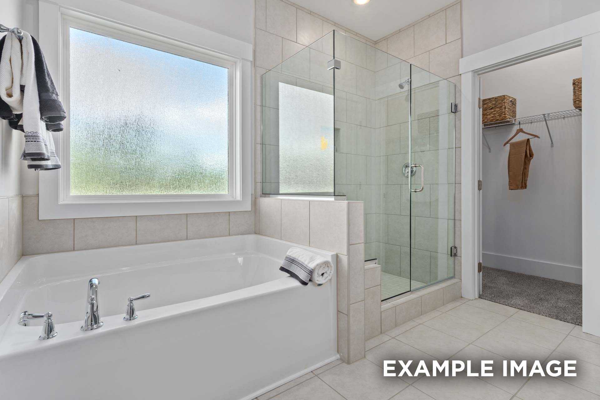 Spacious master bathroom in The Franklin C with soaking tub, frameless glass shower, and adjacent walk-in closet
