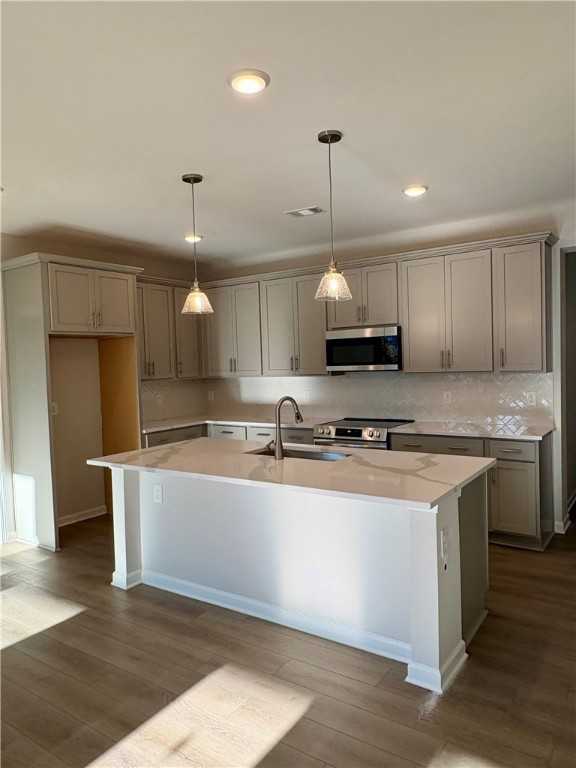 Modern kitchen featuring quartz island, gray shaker cabinets, and stainless appliances in The Luna B 4-bedroom home, Opelika, AL