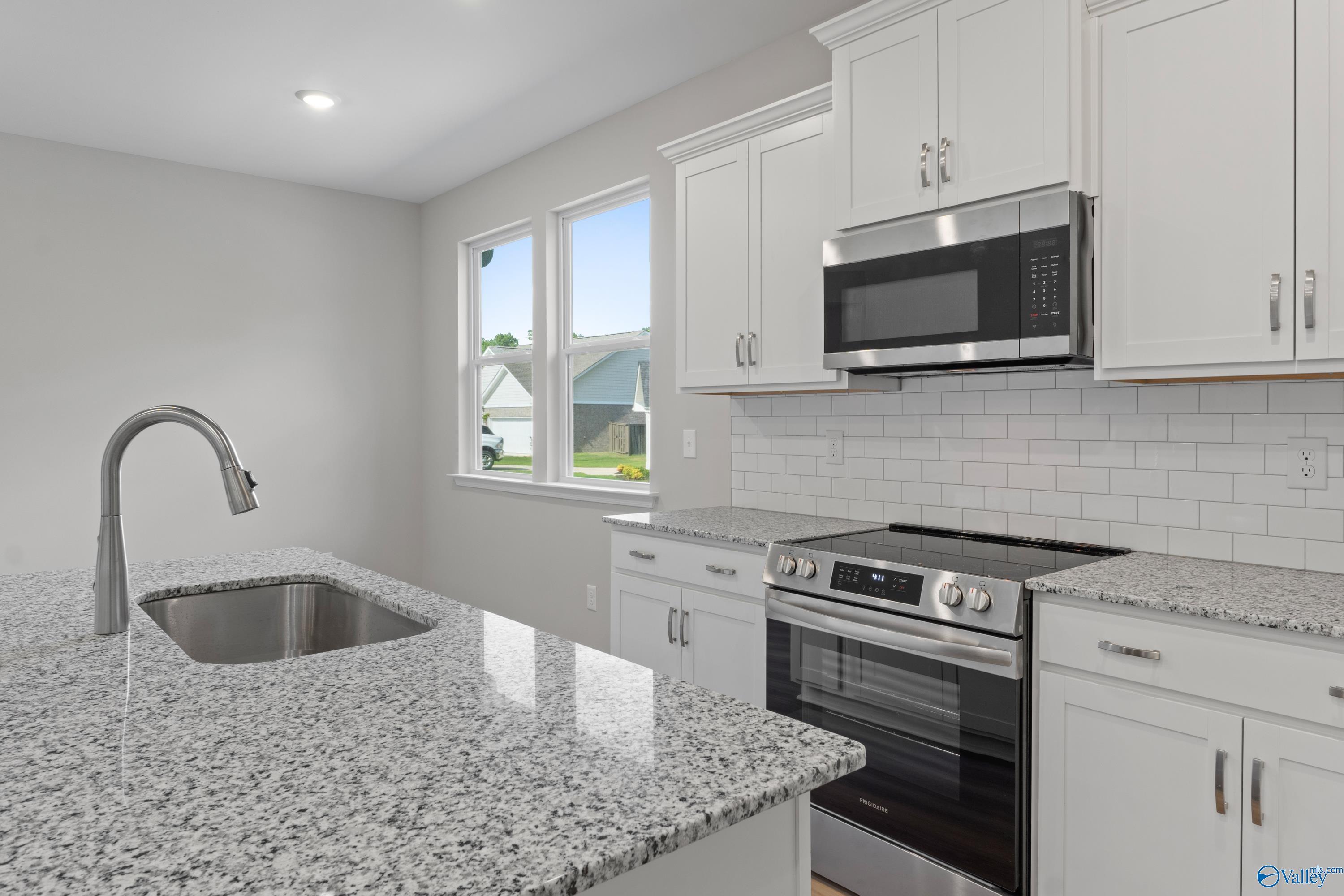 Modern kitchen with granite countertops, stainless steel appliances, white cabinets, subway tile backsplash in The Polaris by Davidson Homes, Fayetteville, TN