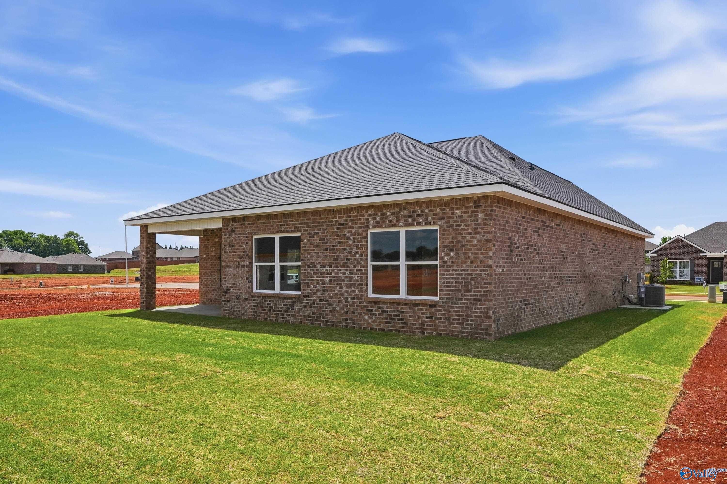 Brick single-story home with covered carport, double windows, and AC unit on lush green lawn in Lynn Meadows, Meridianville, Alabama