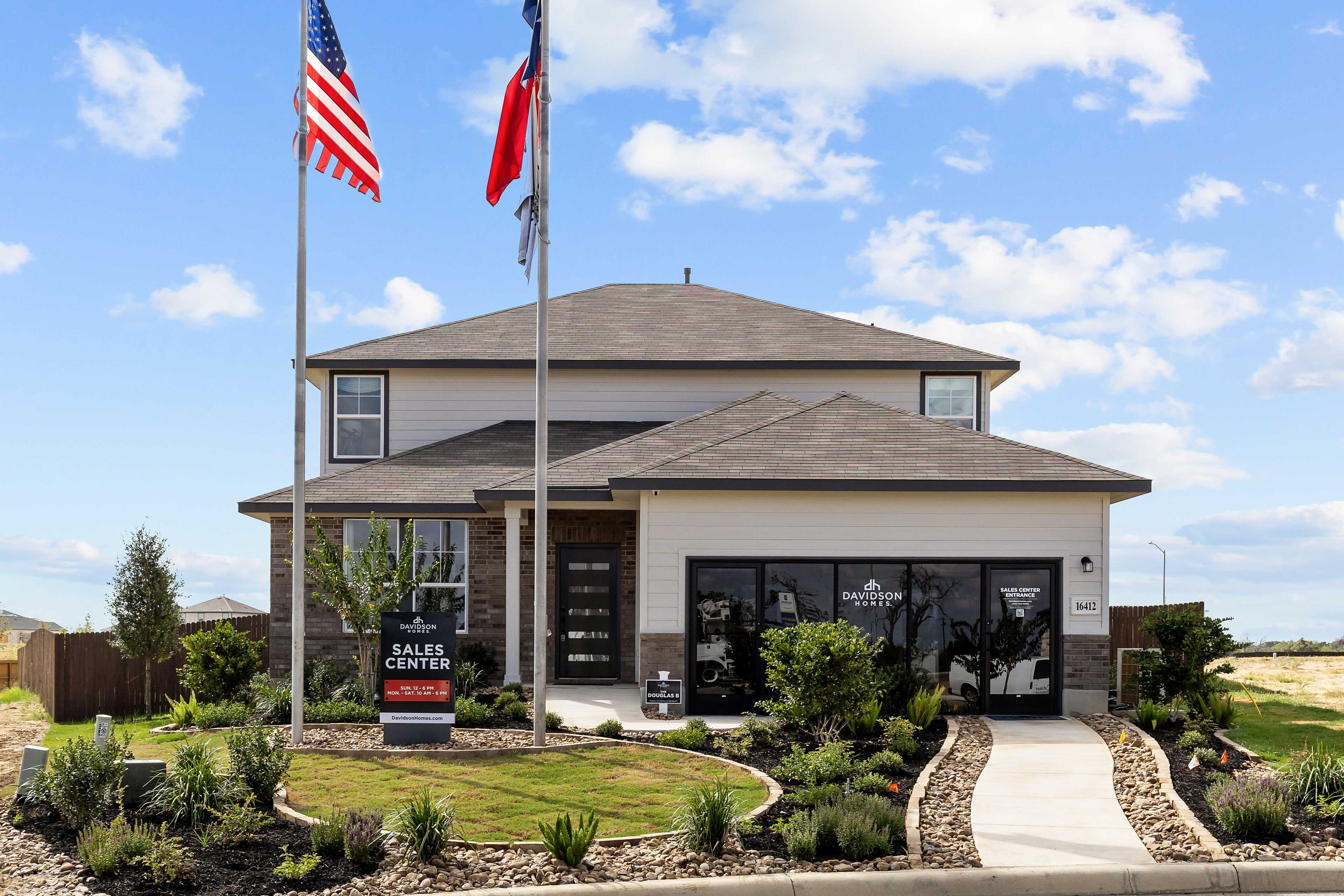 Davidson Homes sales center at Hickory Ridge in Elmendorf Texas with modern two-story facade, flags, and landscaped entry