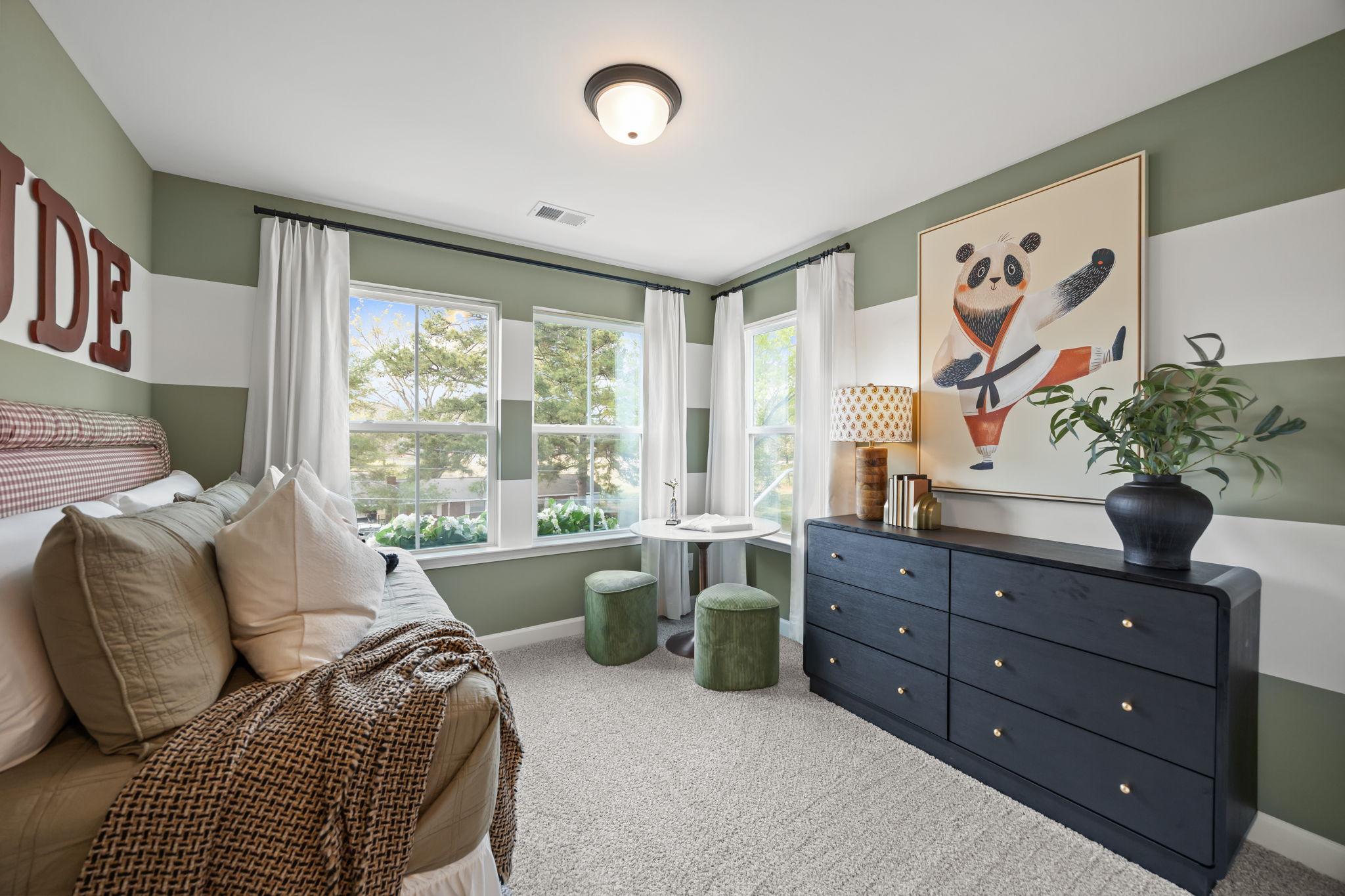 Cozy child's bedroom at Camden Park in Knightdale NC with green striped walls, panda wall art, plush bed, and natural window light