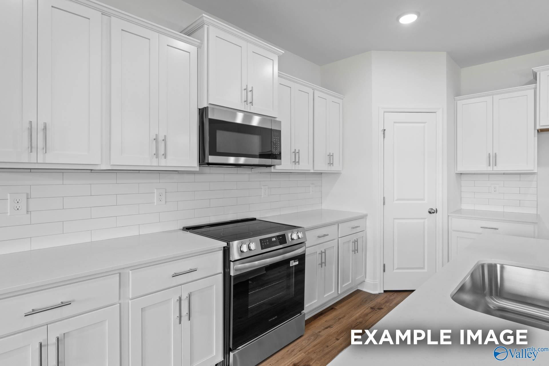 Modern kitchen with white cabinets, stainless steel appliances, and subway tile backsplash in The Rockford B, Toney, AL.