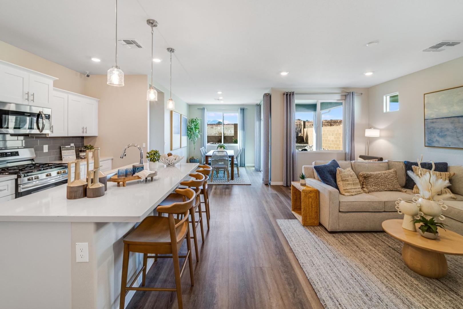 Open-concept kitchen and living area in The Newport C by Davidson Homes, featuring white island, bar stools, and cozy beige sofa in Prescott AZ