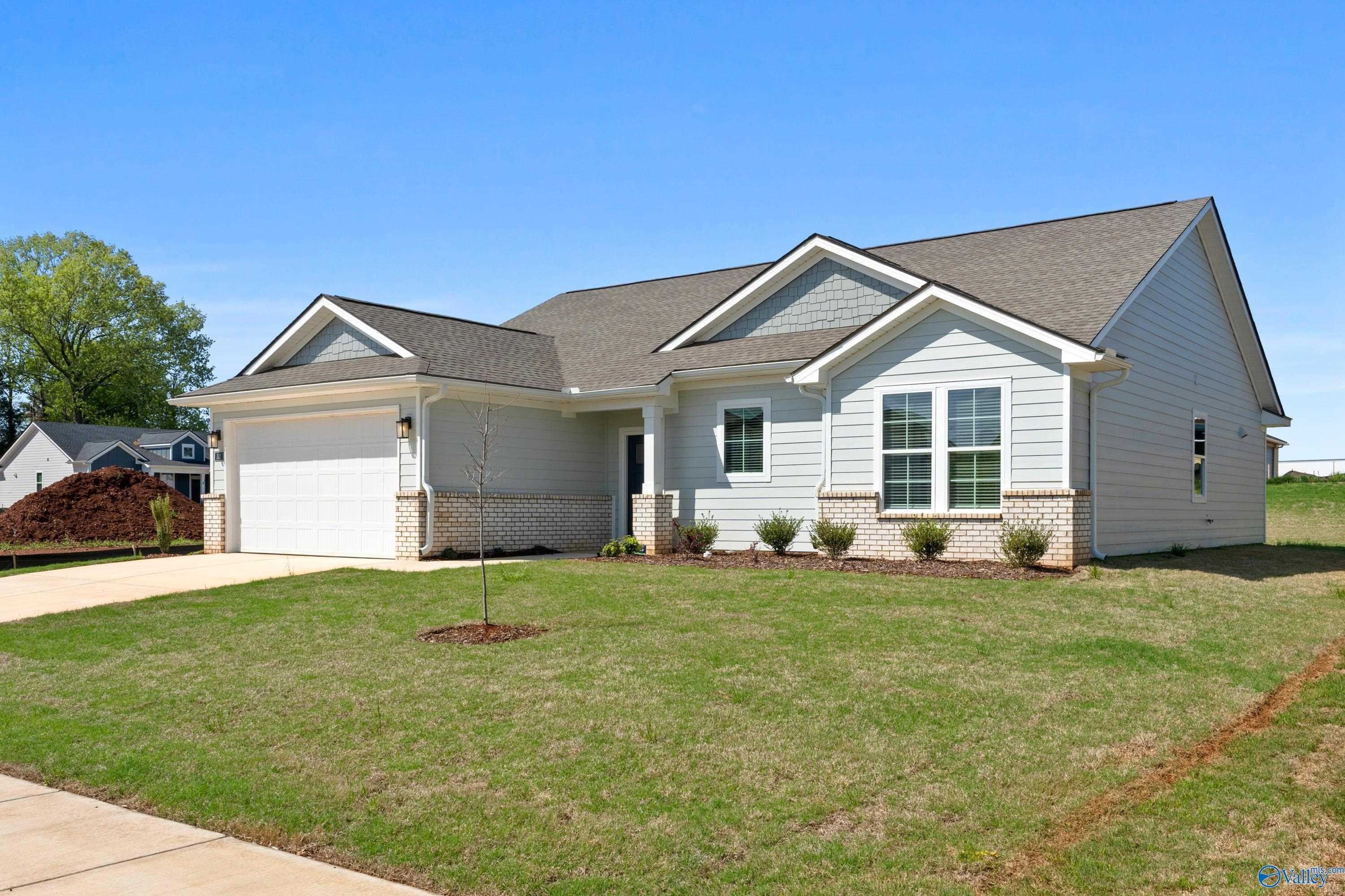 Modern white single-story home with gabled gray roof, 2-car garage, and landscaped front yard in Evergreen Mill, Madison, Alabama