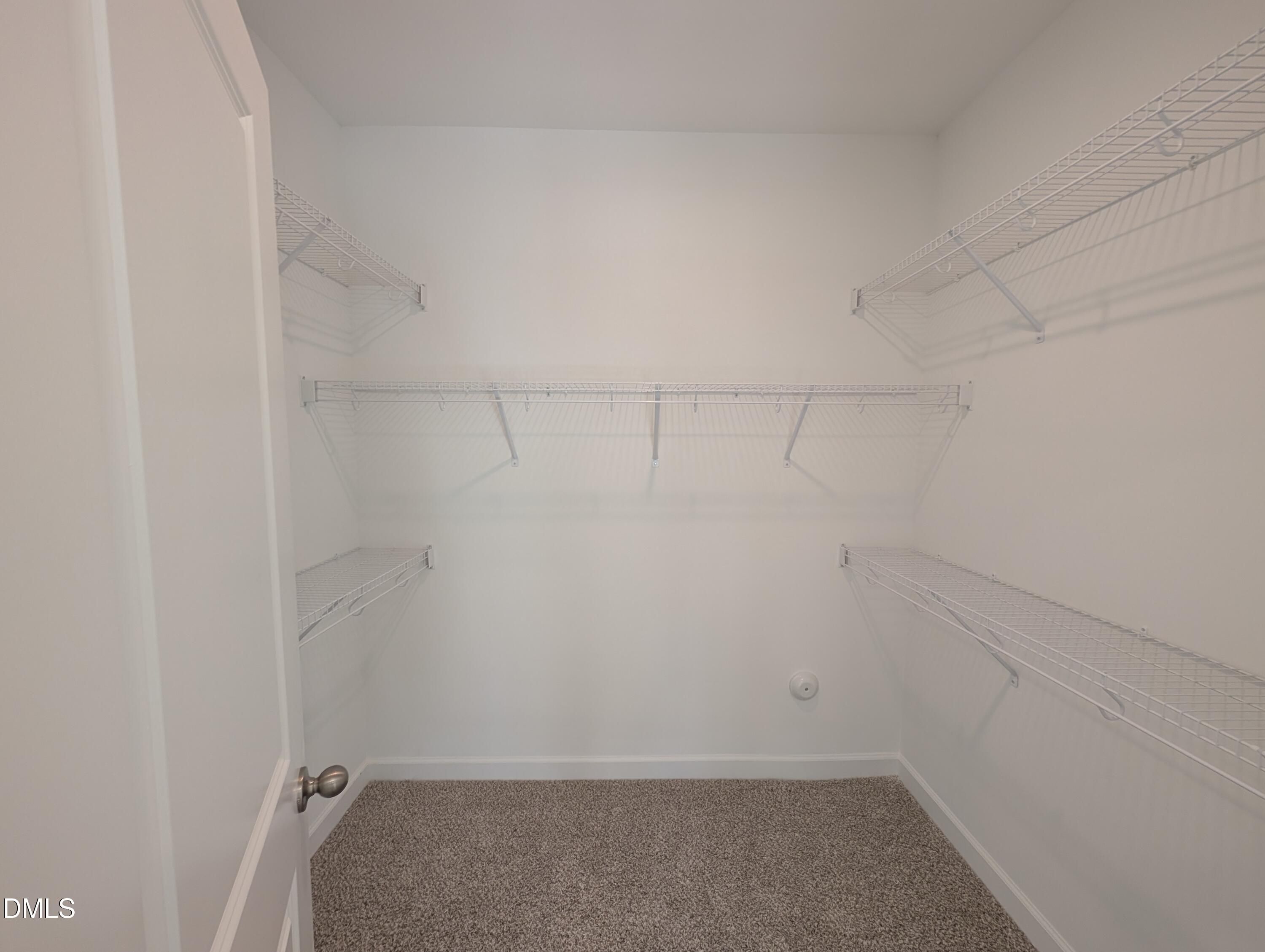 Spacious walk-in closet with white wire shelving and carpet in Davidson Homes The Magnolia A, Wendell Ridge, North Carolina