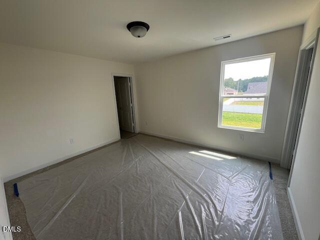 Bright bedroom with neutral walls and protective floor covering in The Hickory II B at Retreat at North Main, Lillington.