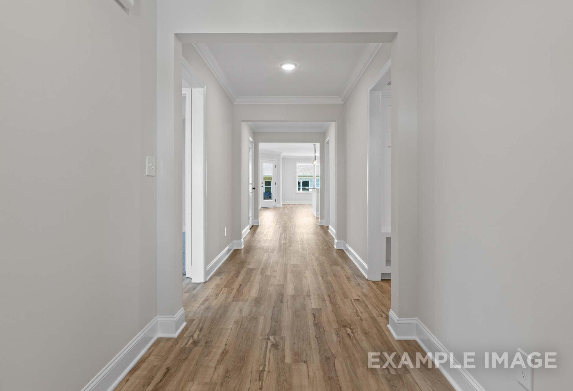 Spacious hallway in The Holly home with light hardwood floors, white walls, and arched doorways