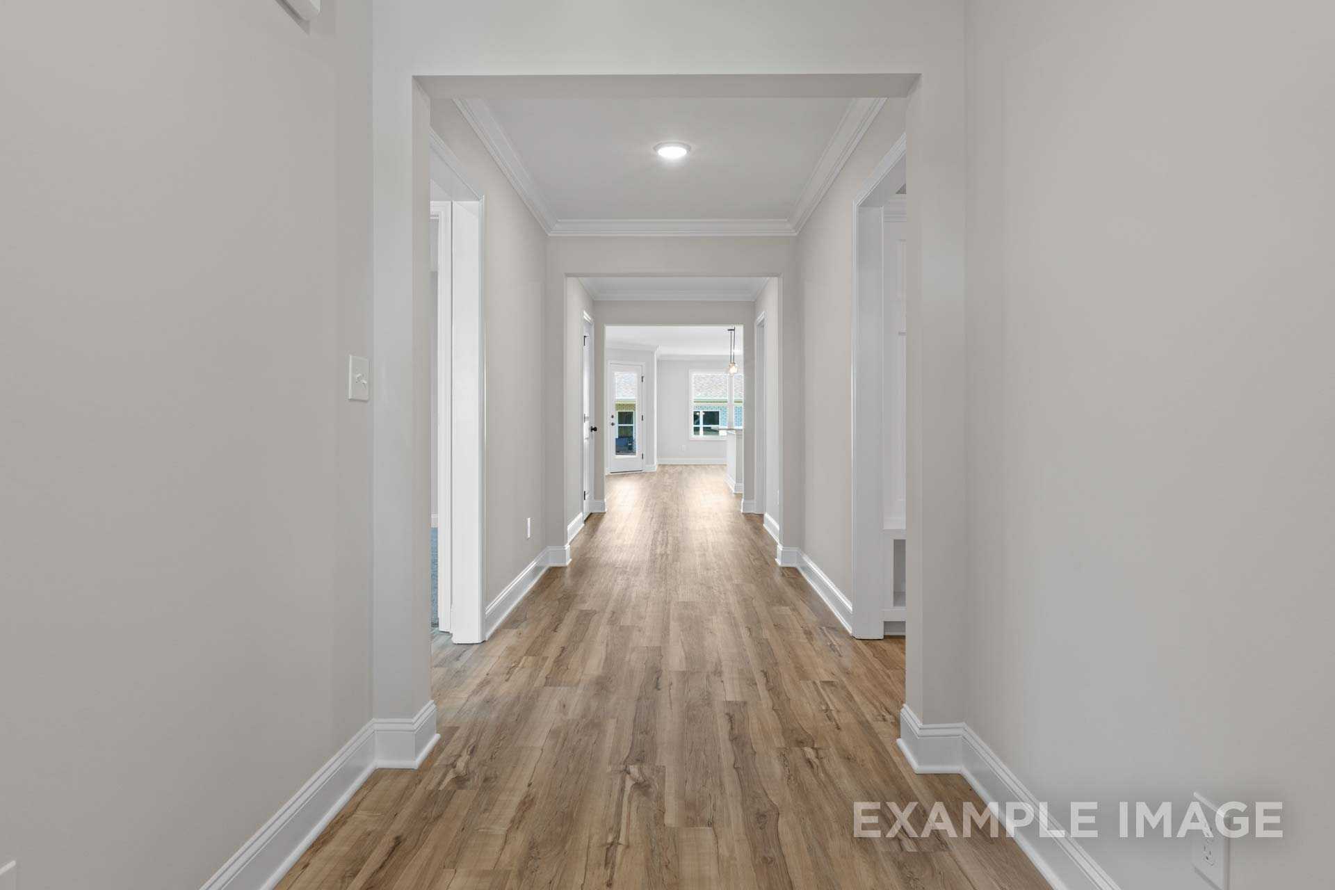 Spacious hallway in The Holly home with light hardwood floors, white walls, and arched doorways