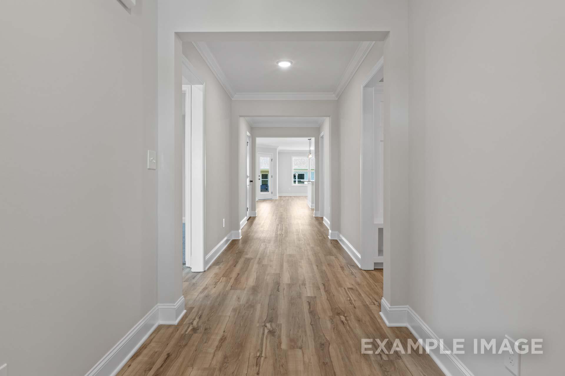 Spacious hallway in The Holly home with light hardwood floors, white walls, and arched doorways