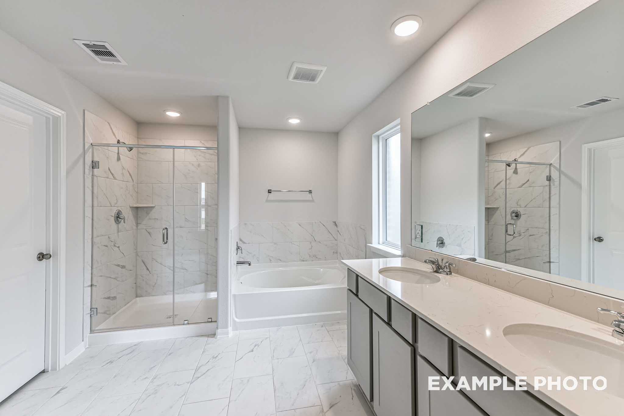 Spacious master bathroom in The Costa C with glass shower, soaking tub, double vanity, and tiled floors
