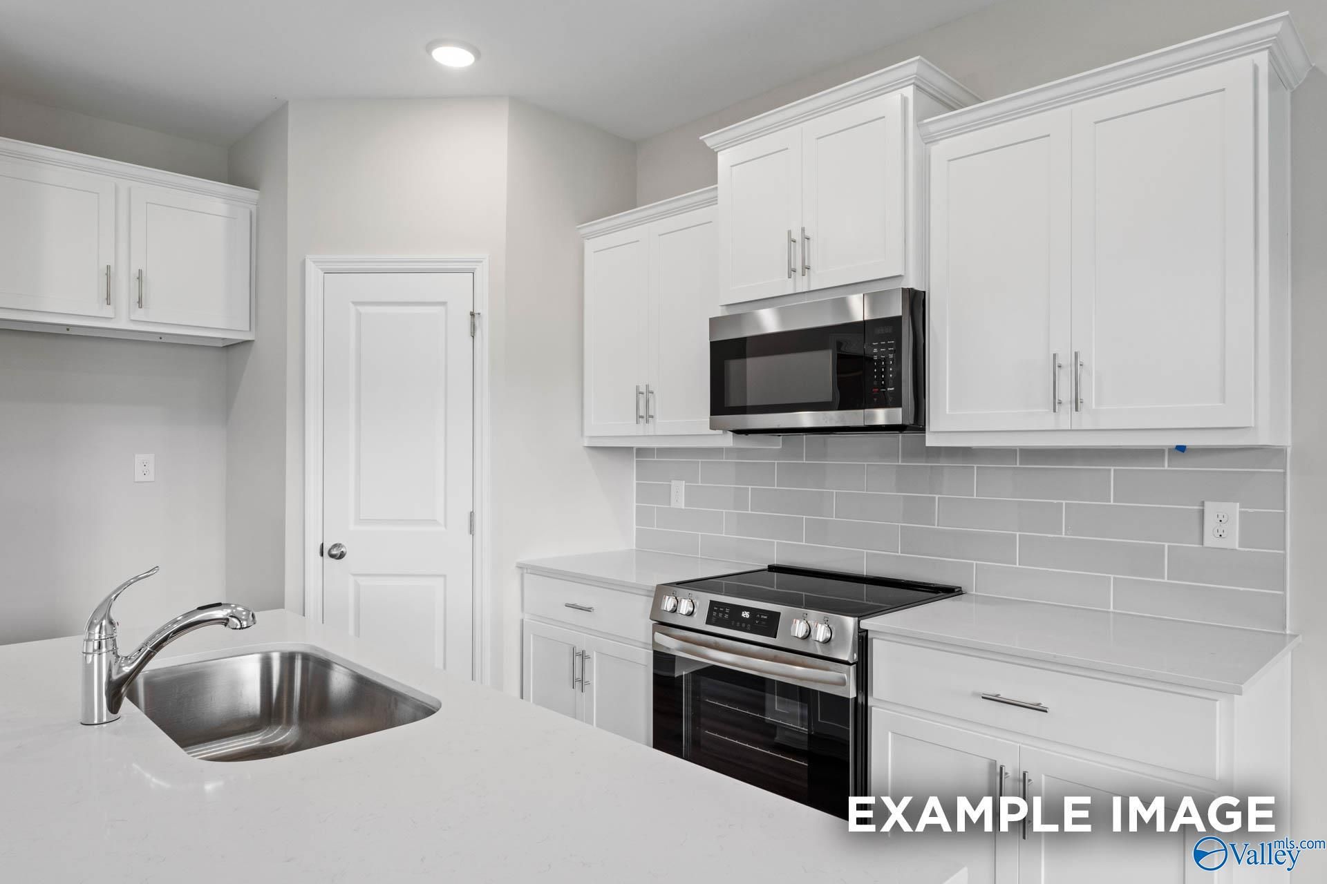 Modern white kitchen with stainless steel range, microwave, subway tile backsplash in Davidson Homes The Butler, Huntsville, AL