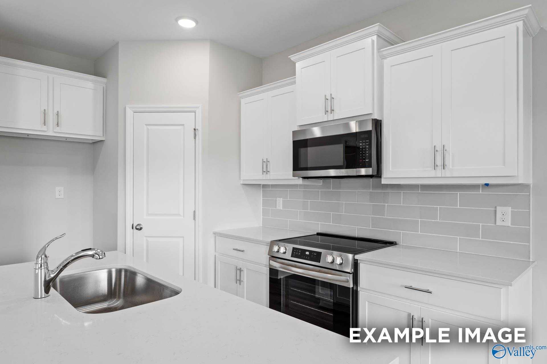 Modern white kitchen with stainless steel range, microwave, subway tile backsplash in Davidson Homes The Butler, Huntsville, AL