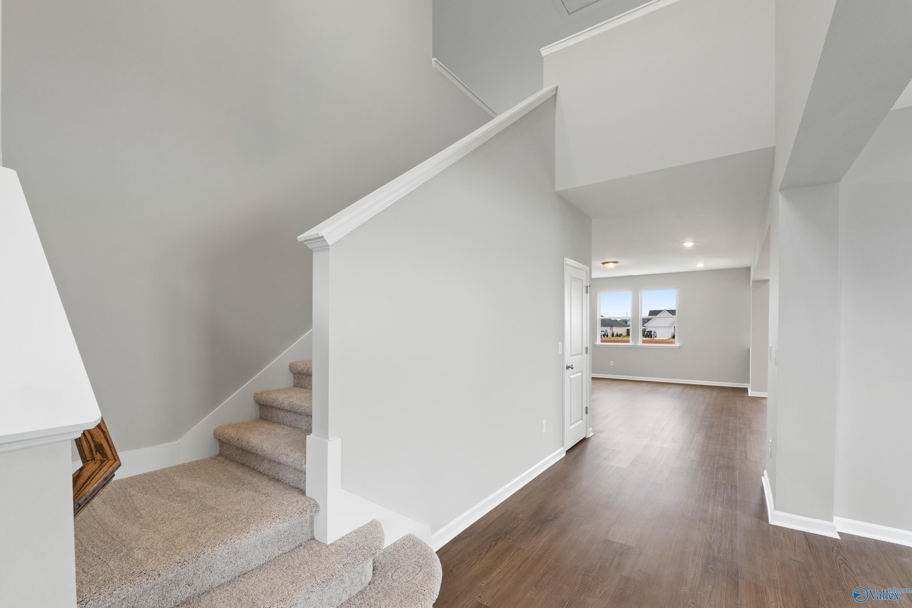 Spacious two-story foyer with elegant white staircase, carpeted steps, hardwood floors, and sunlit windows in Davidson Homes The Dorado, Athens AL
