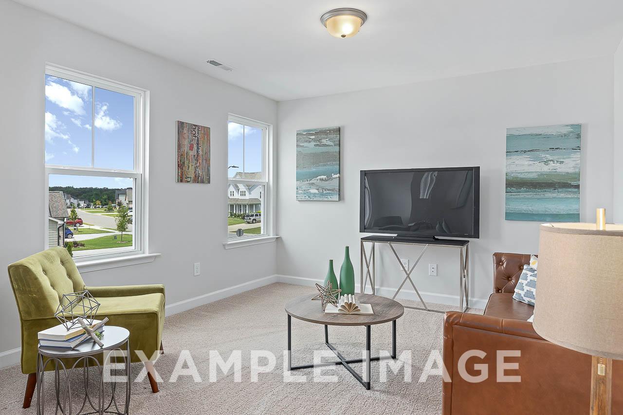 Spacious living room in The Willow C featuring large windows with neighborhood view, green armchairs, leather sofa, and abstract art