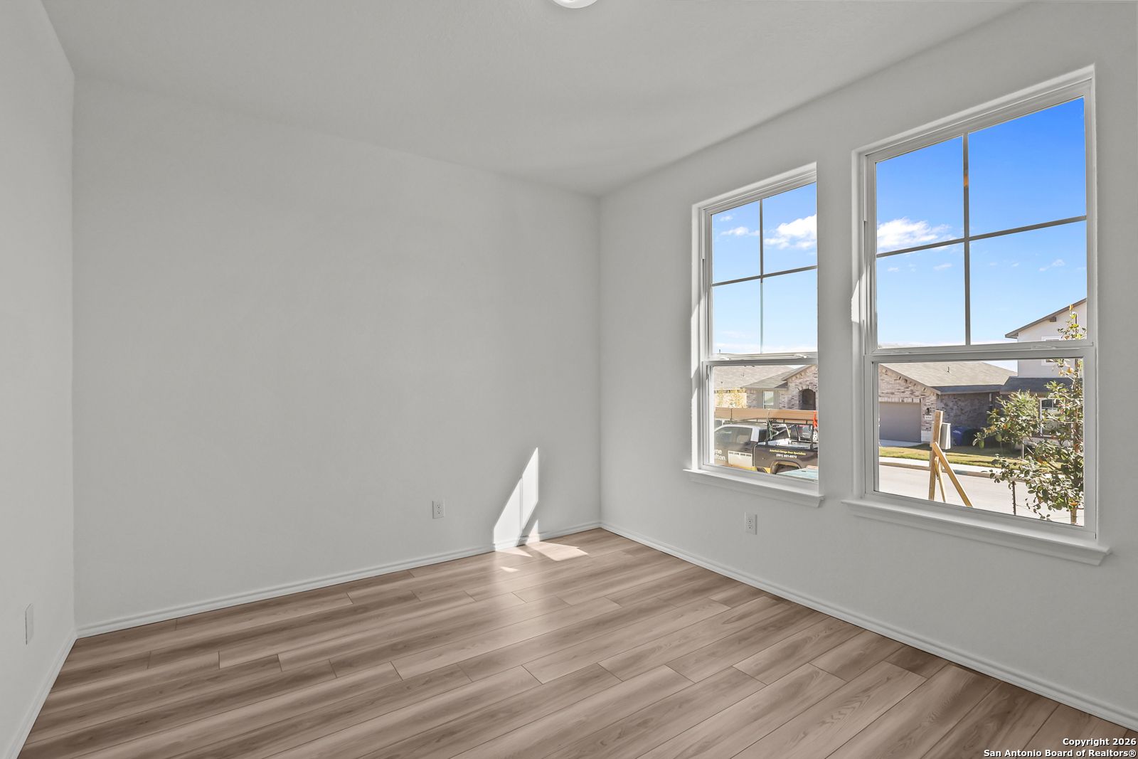 Bright empty bedroom with large windows, hardwood floors, and natural light in Davidson Homes The Douglas E, San Antonio