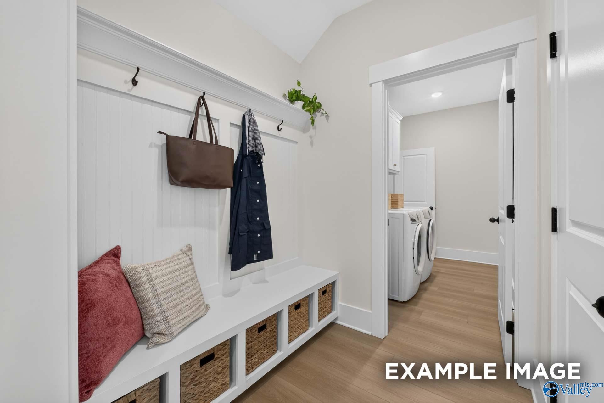 Built-in mudroom bench with storage baskets, coat hooks, and laundry room access in Davidson Homes The Ashport K, Hazel Green