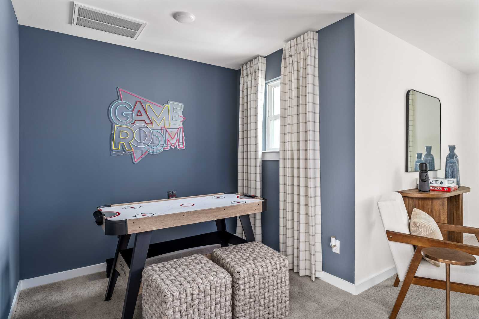 Vibrant game room at Woods Crossing in Gallatin, Tennessee with neon sign, foosball table, and modern seating