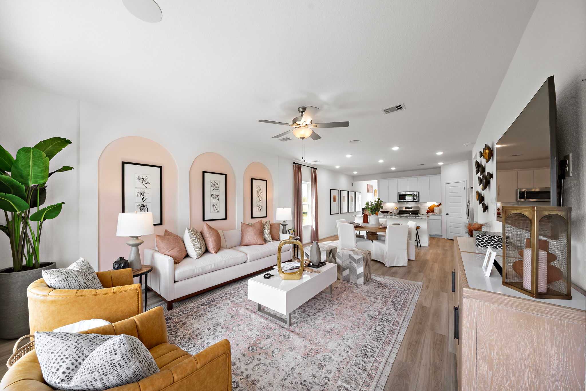 Open-concept living room at The Villages at WestPointe in Dayton Texas featuring pink arched walls, white sofa, and hardwood floors