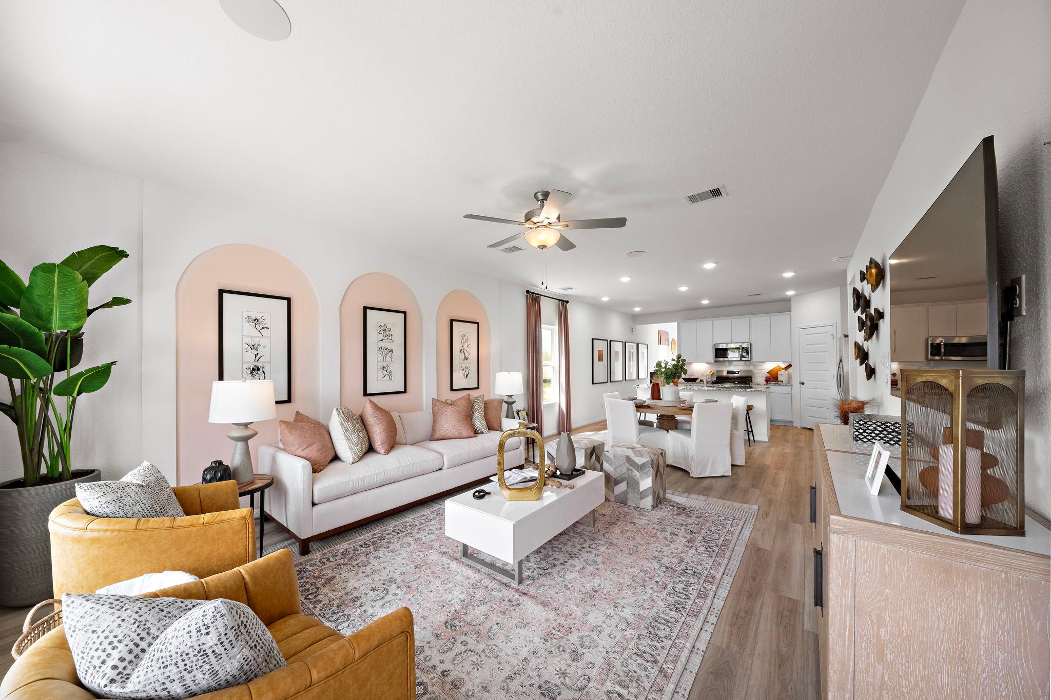 Open-concept living room at The Villages at WestPointe in Dayton Texas featuring pink arched walls, white sofa, and hardwood floors
