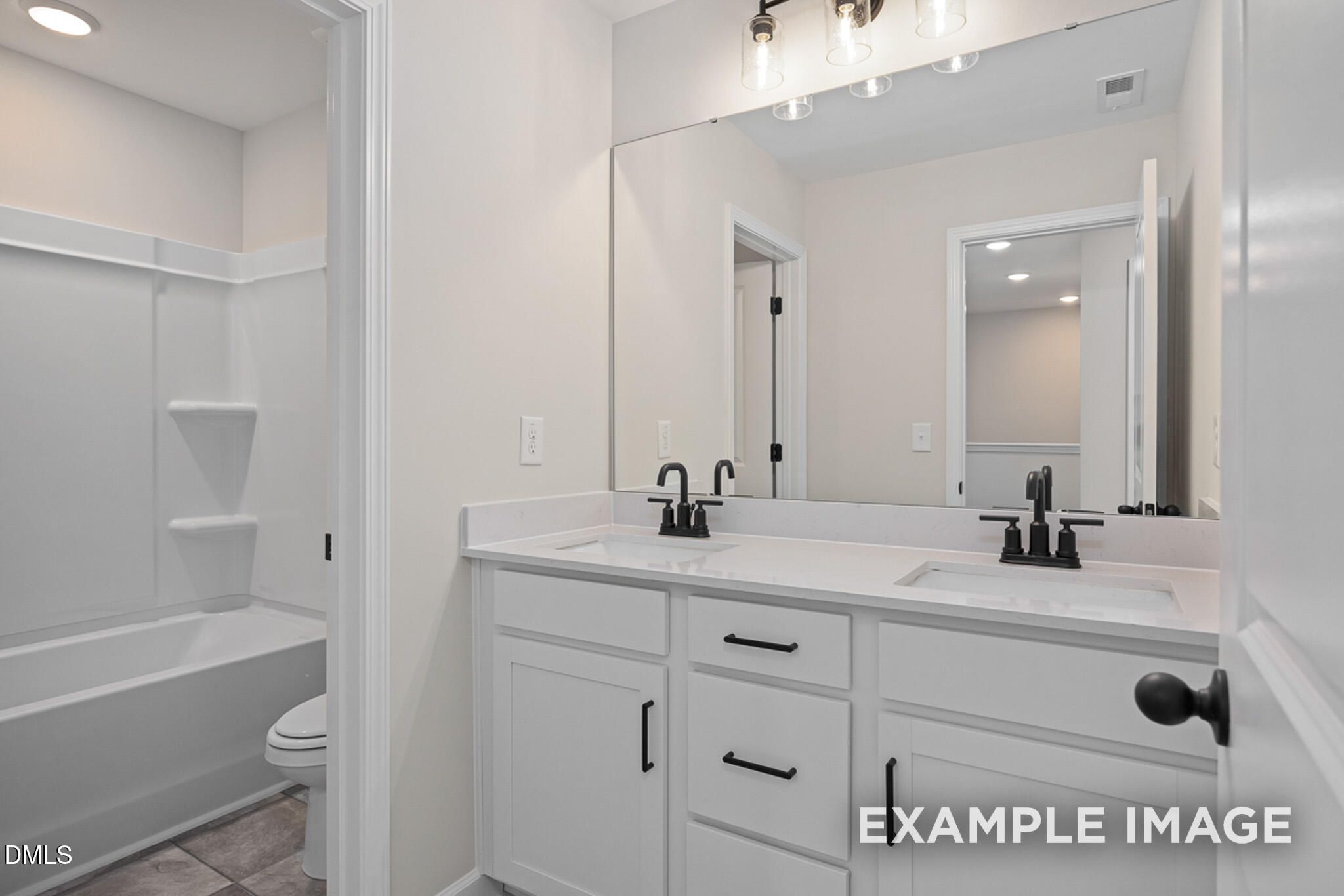 Modern bathroom with double vanity, white cabinets, and tub-shower combo in Mitchell floor plan at Camden Park, Knightdale.
