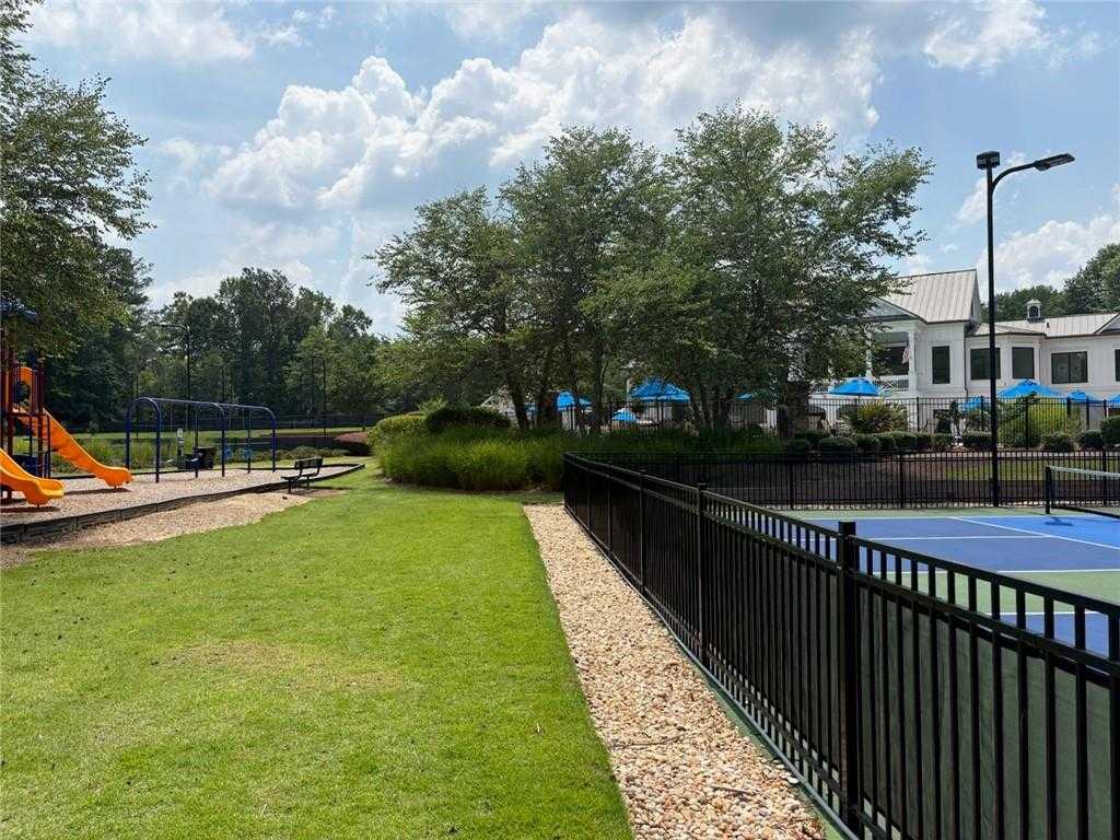 Vibrant playground with orange slides, fenced basketball court, lush trees and grass in Riverwood community, Dallas, Georgia