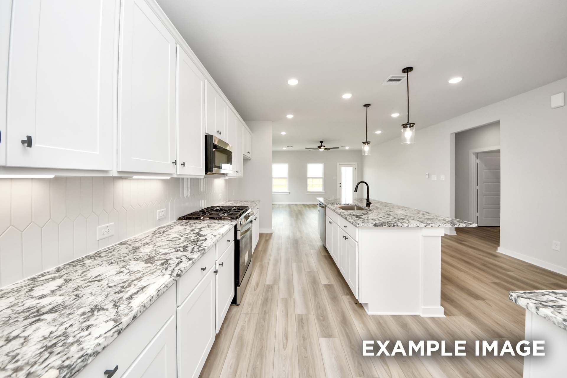 Modern kitchen in The Sorrento F featuring white cabinetry, granite countertops, and a large island in an open floor plan.