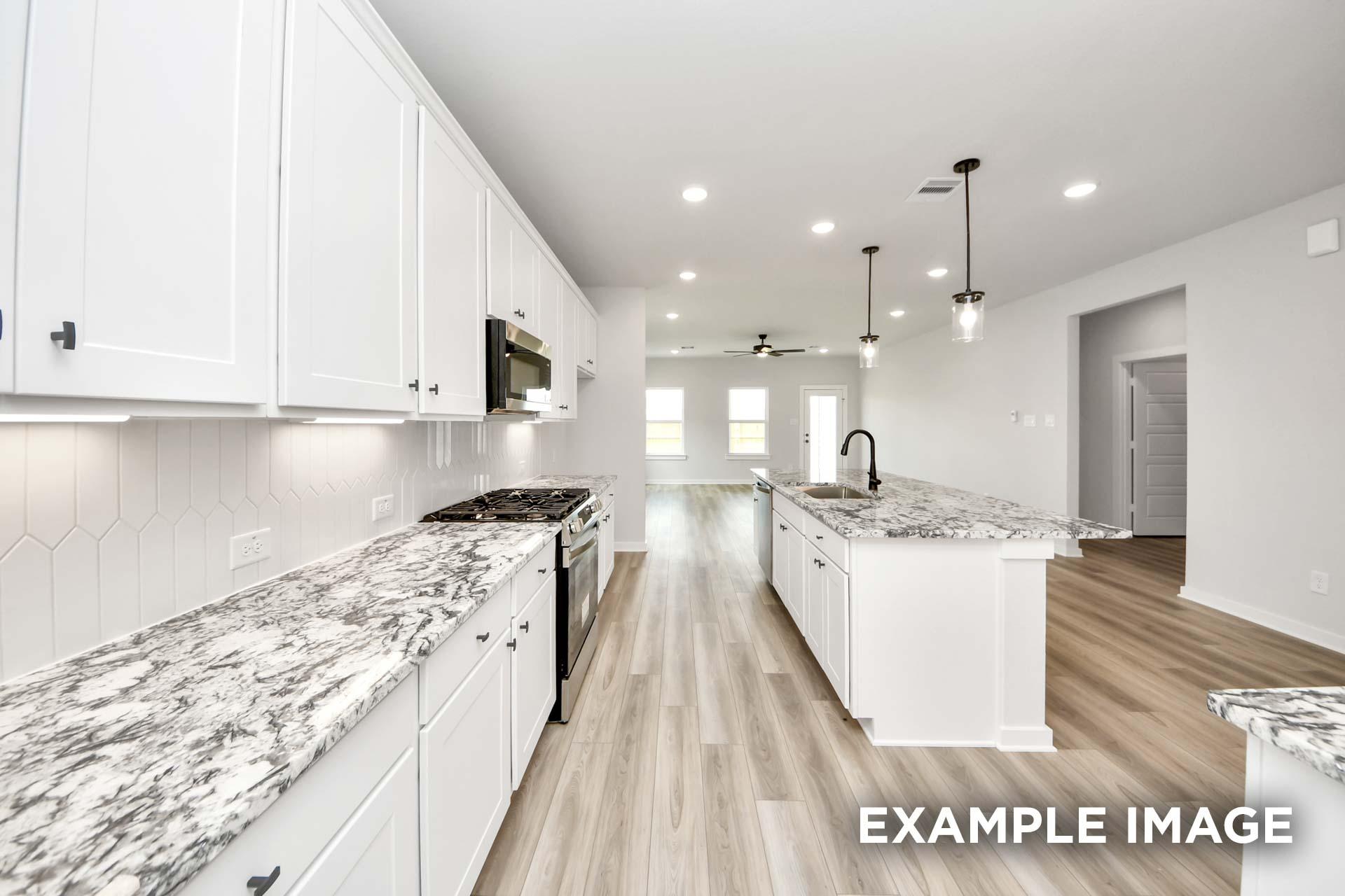 Modern kitchen in The Sorrento F featuring white cabinetry, granite countertops, and a large island in an open floor plan.