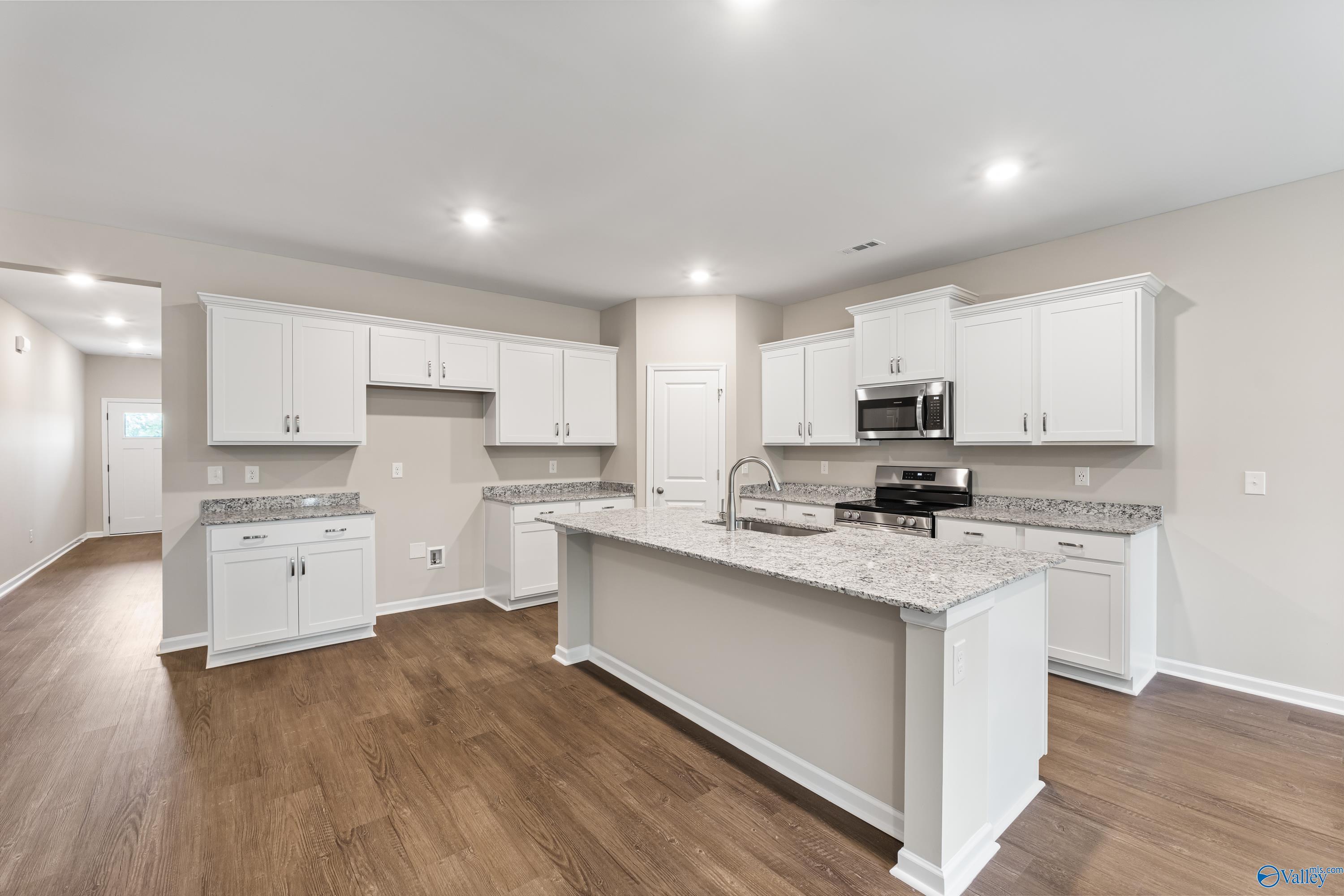 Modern white shaker kitchen with quartz countertops, stainless appliances, and center island in Davidson Homes The Phoenix, Fayetteville, TN
