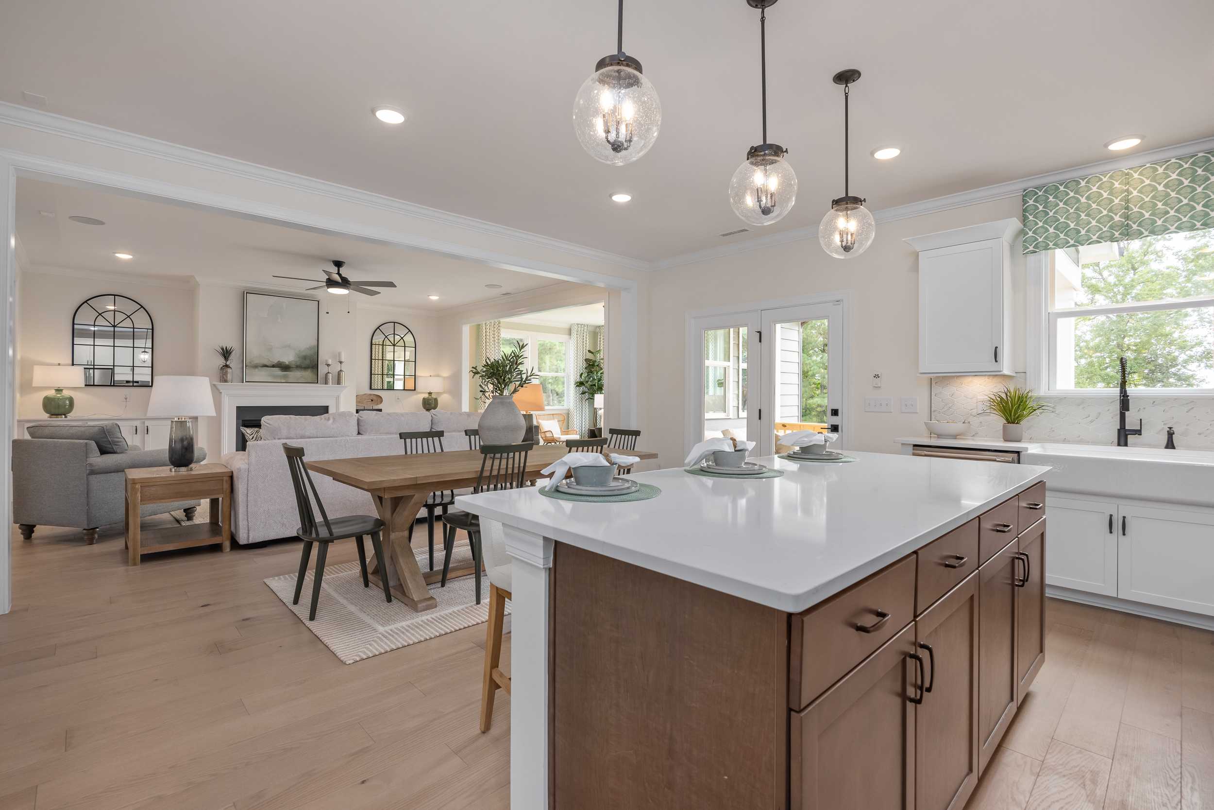 Open-concept kitchen and living room at Laneridge Estates in Raleigh NC with white cabinets, quartz island, dining table, and hardwood floors