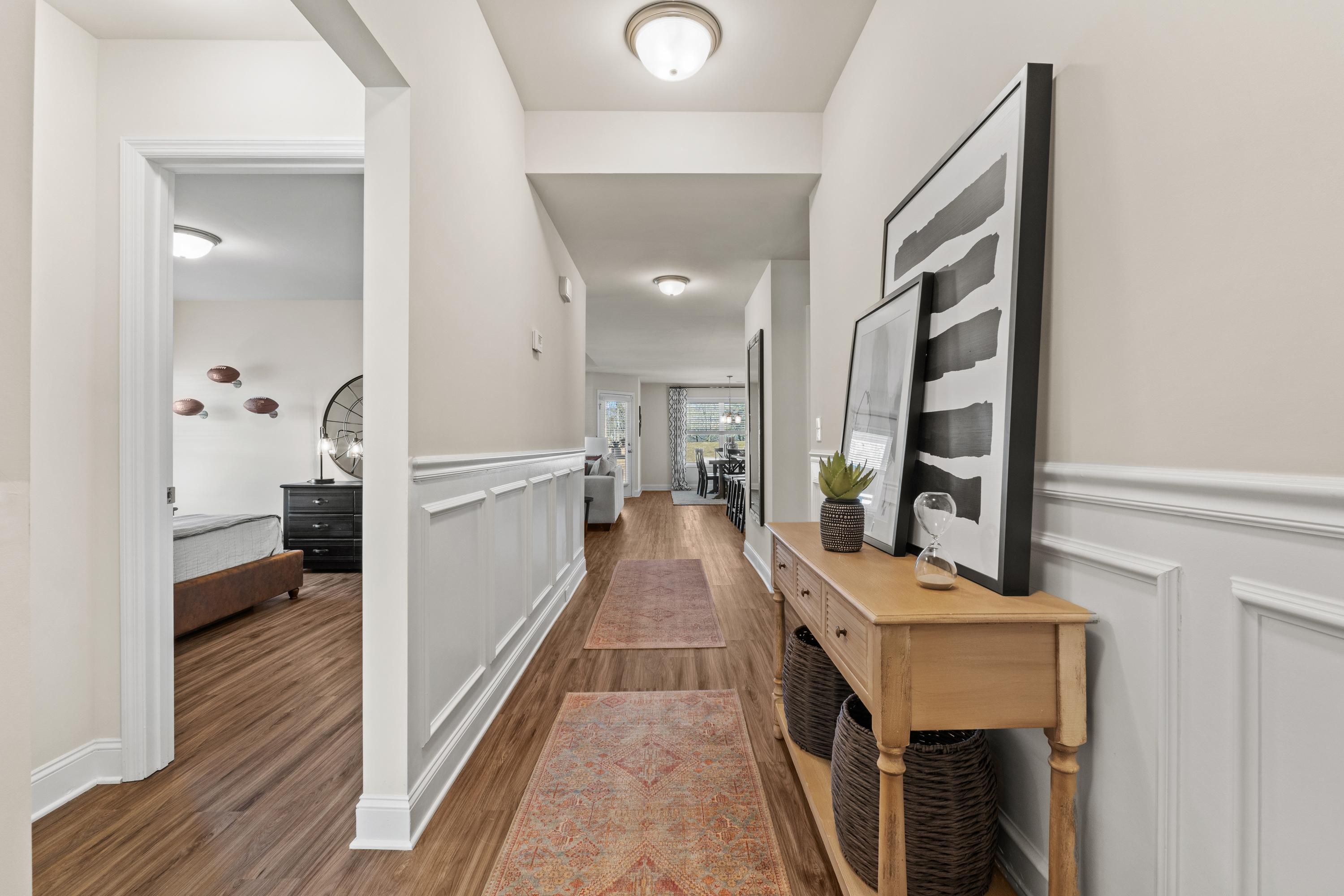 Elegant hallway at Berry Cove in New Market Alabama with wainscoting, hardwood floors, runner rug, and console table