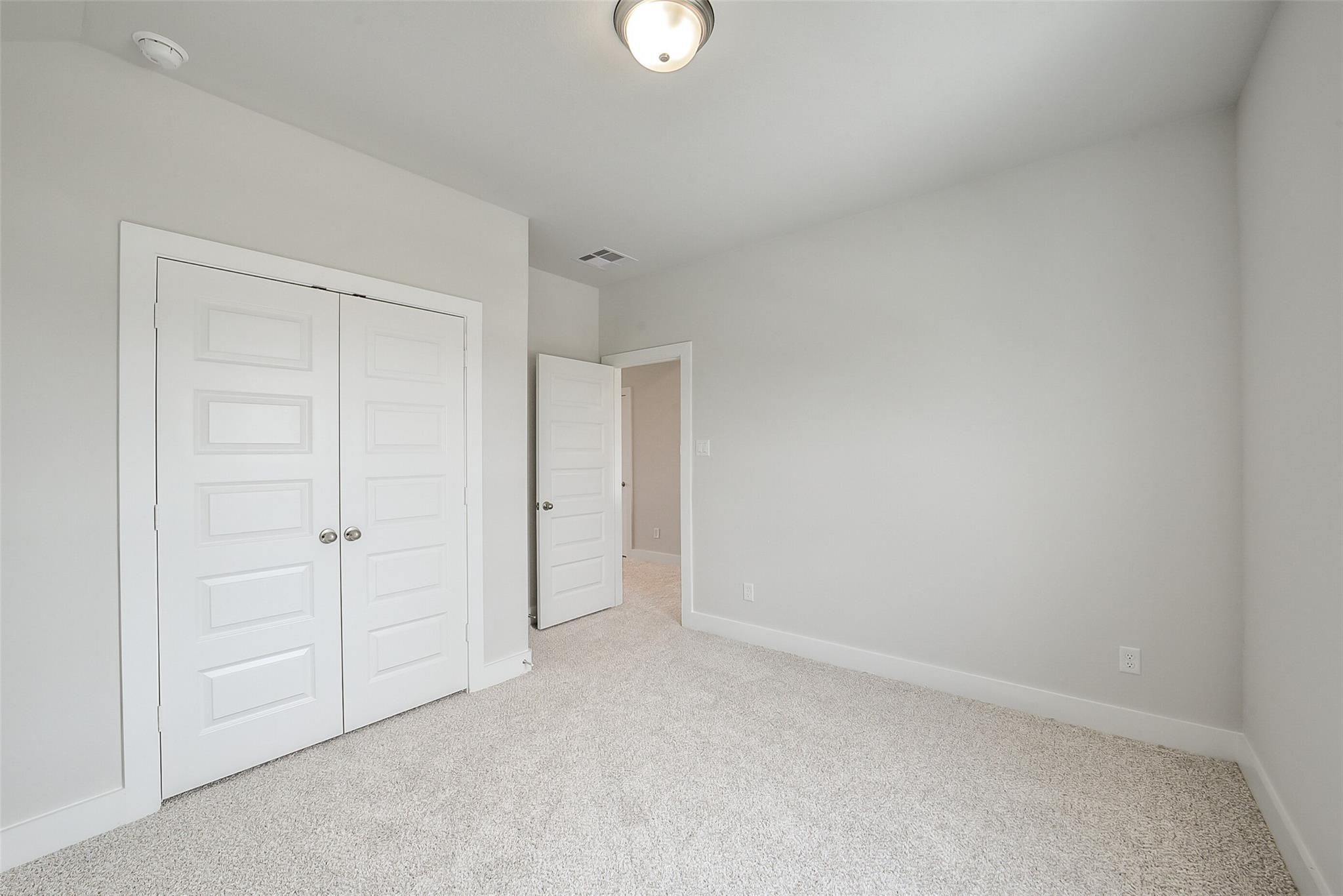 Bright secondary bedroom with double closet doors and adjacent bath in Davidson Homes The Philip B, Rosharon, Texas