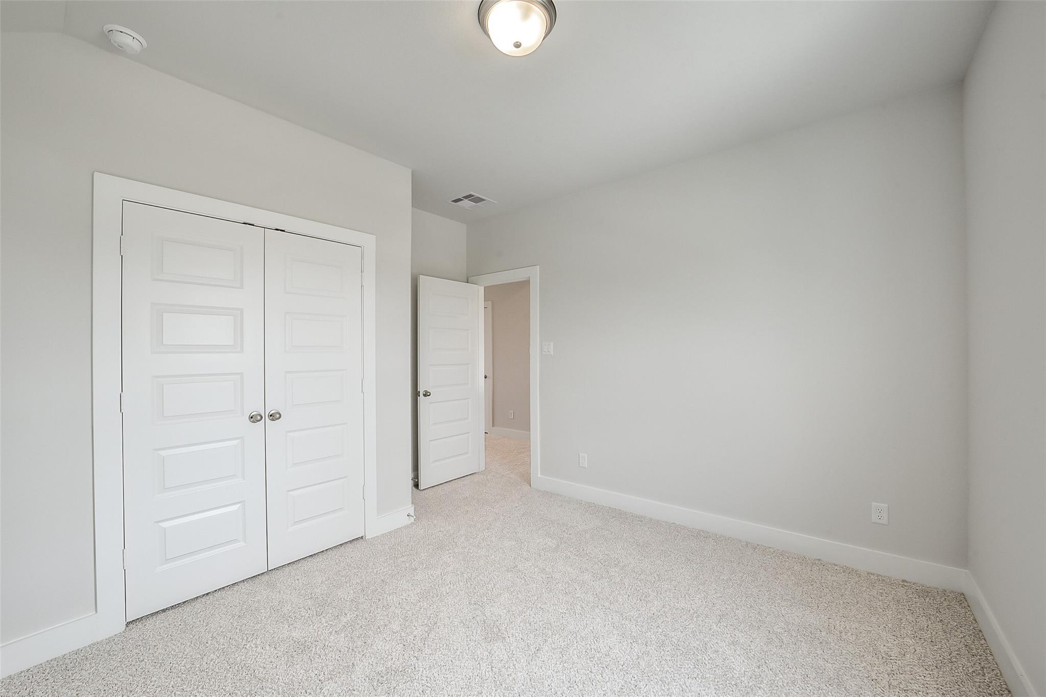 Bright secondary bedroom with double closet doors and adjacent bath in Davidson Homes The Philip B, Rosharon, Texas