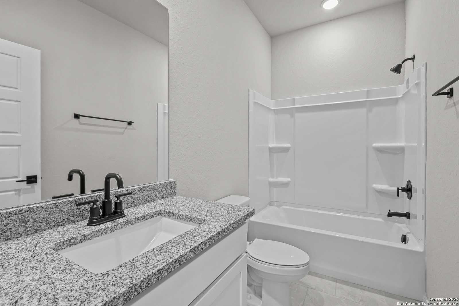 Modern bathroom featuring granite vanity, deep soaking tub, and walk-in shower in Davidson Homes The Daphne K, San Antonio, Texas