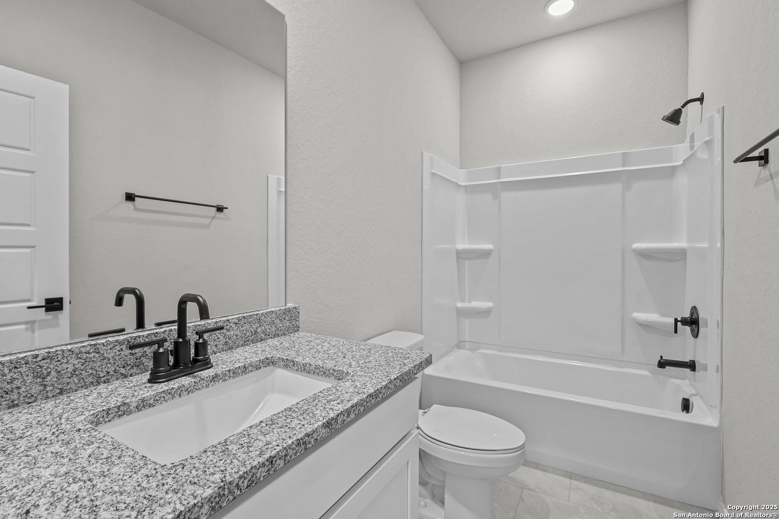 Elegant master bathroom with granite vanity, soaking tub, and shower in Davidson Homes The Daphne K, San Antonio, Texas