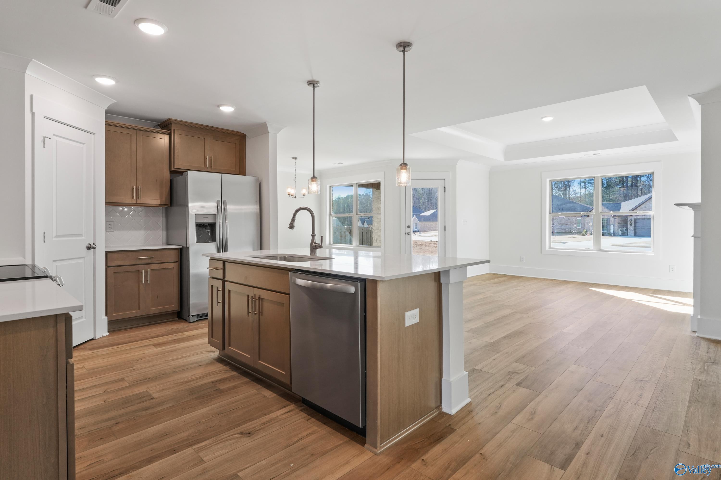 Open-concept kitchen with wood shaker cabinets, white quartz island, stainless appliances, pendant lights in The Daphne C 4-bedroom home, Arab, Alabama