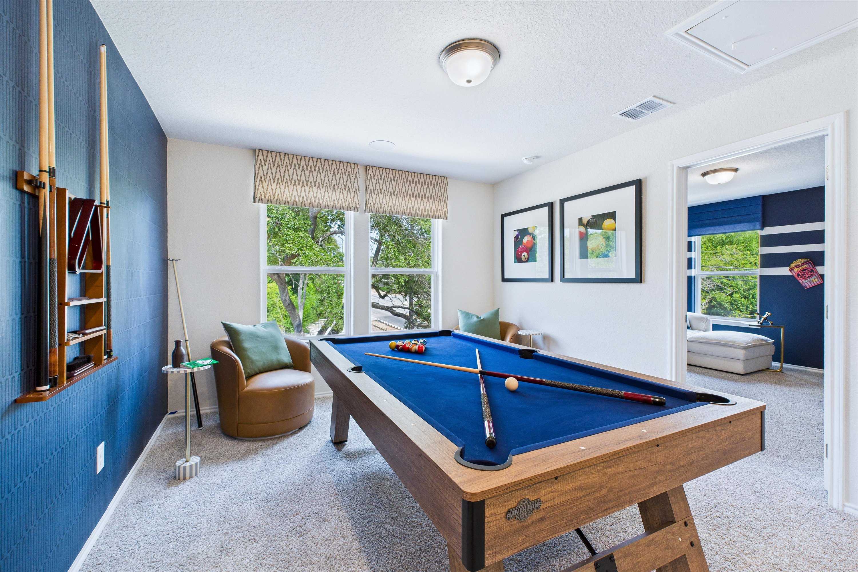 Spacious billiards room at Cedar Heights in San Antonio TX with wooden pool table, navy walls, and lounge chairs