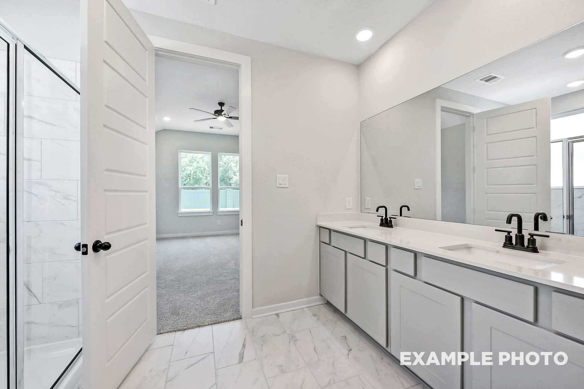 Spacious master bathroom in The Sequoia with double vanity, frameless glass shower, and open bedroom doorway