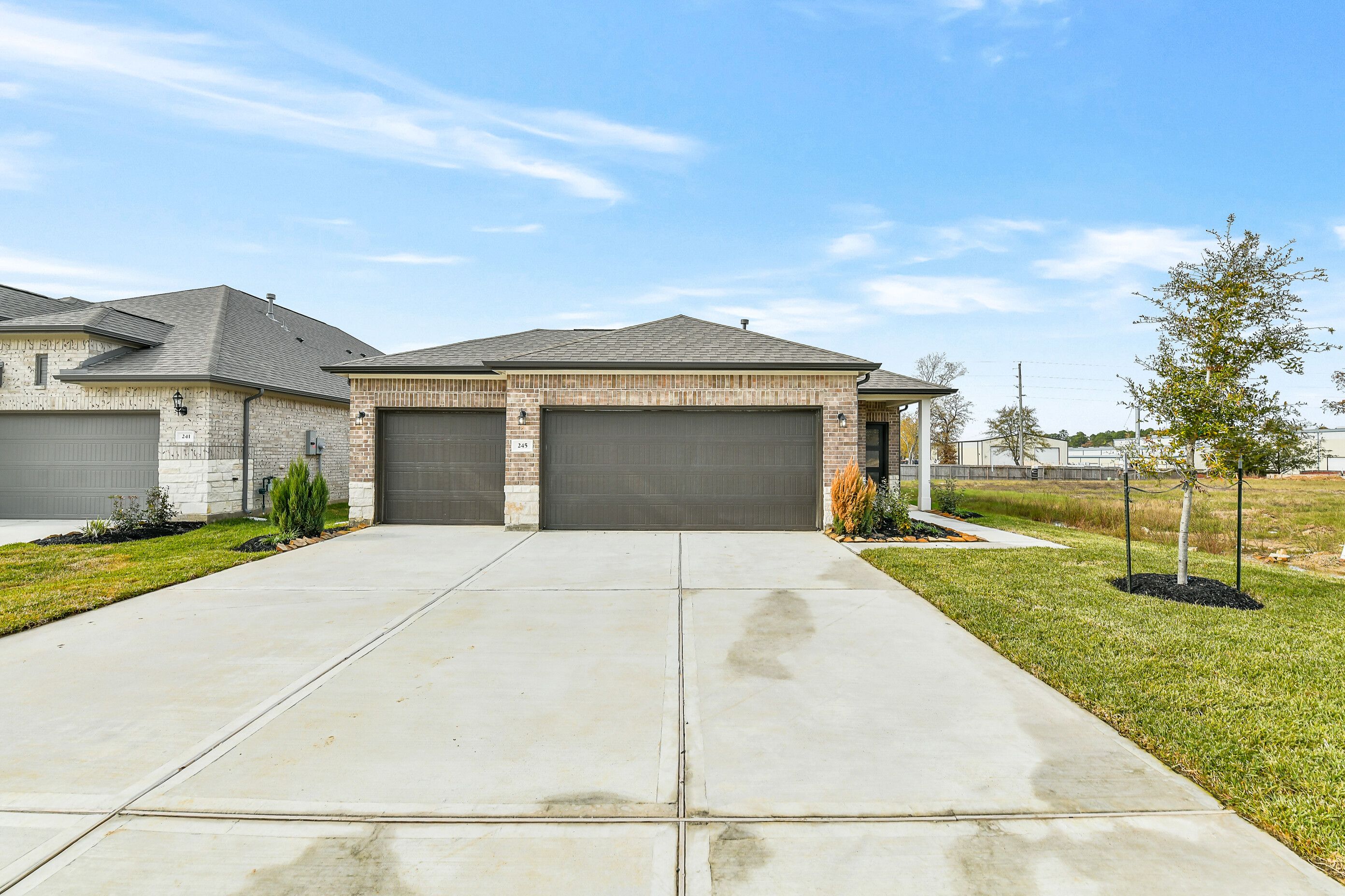 Brick single-story 4-bedroom home with 3-car garage, wide driveway, and landscaped yard in Windmill Estates, Magnolia, Texas